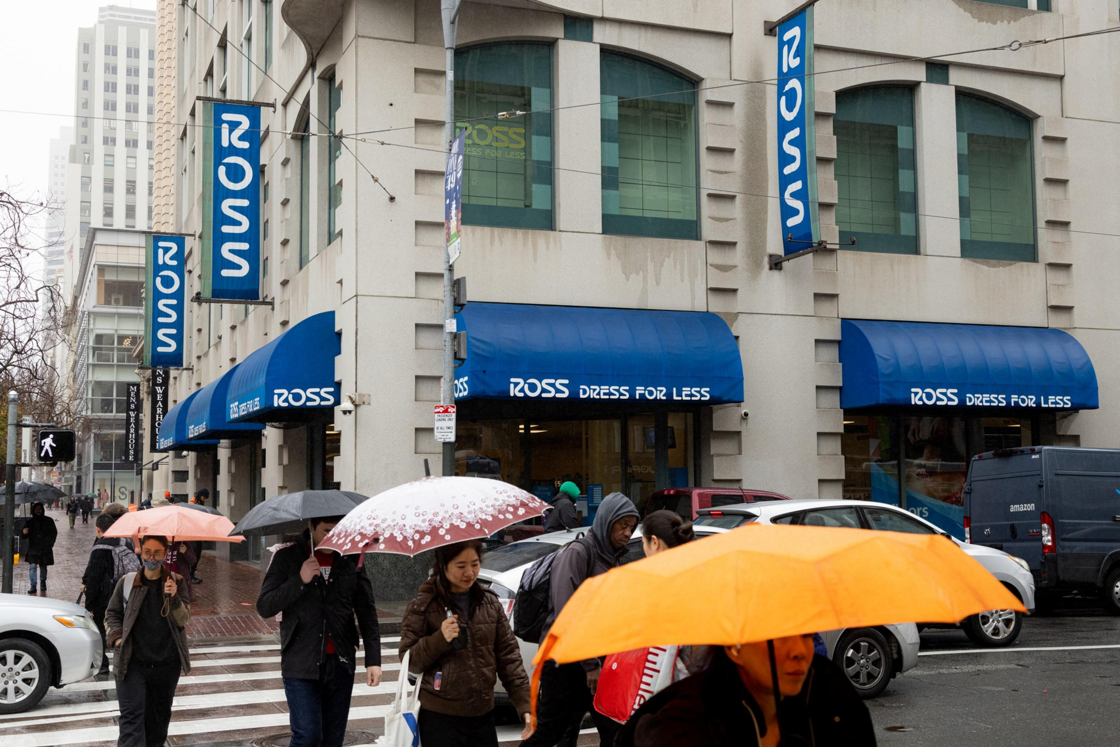 People walk through a crosswalk while carrying umbrellas outside a Ross Dress for Less store on Market and Fourth Streets in San Francisco.