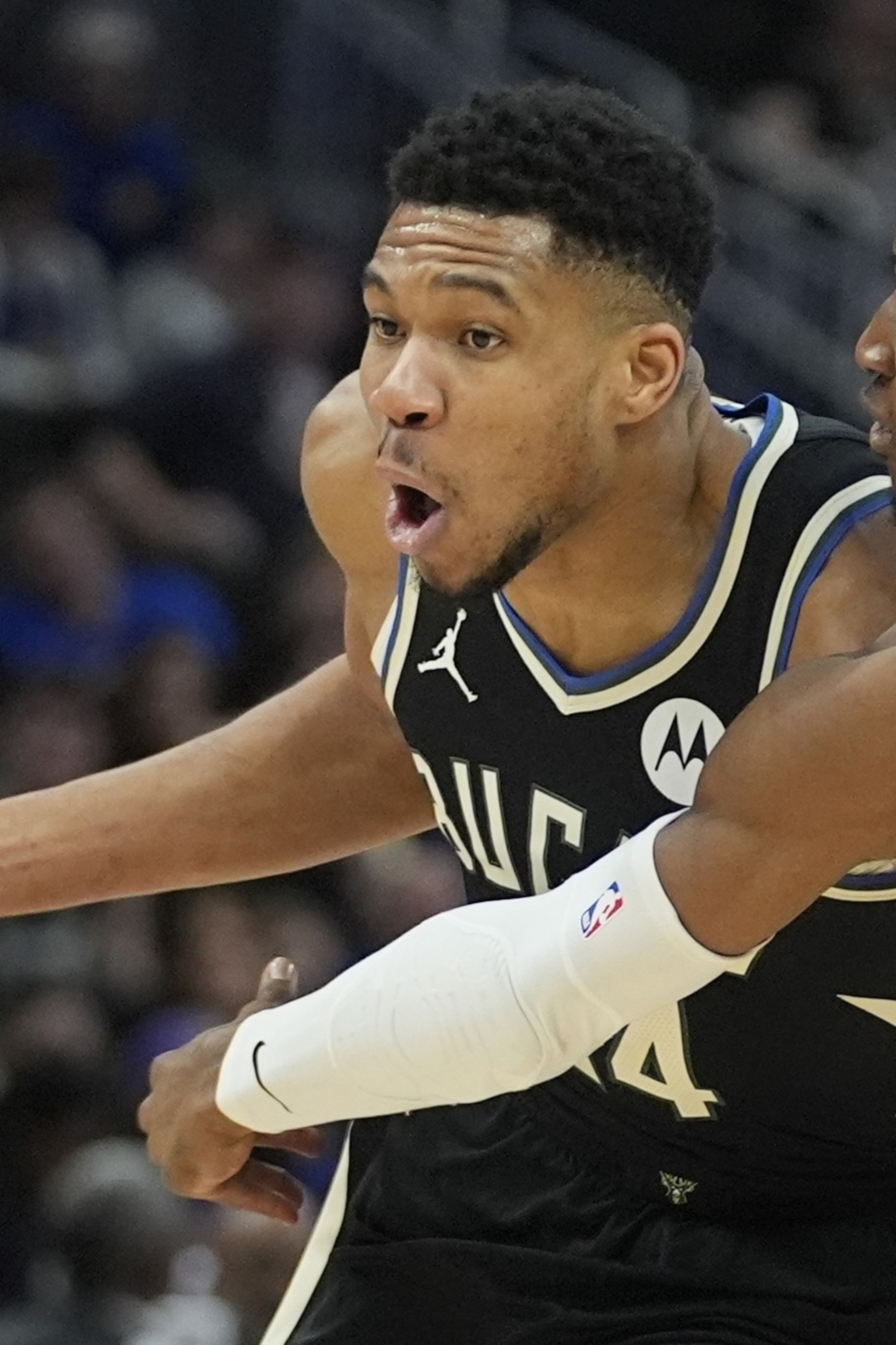 Two basketball players are competing intensely. One in a black jersey is dribbling the ball, while the one in a white jersey is closely defending.