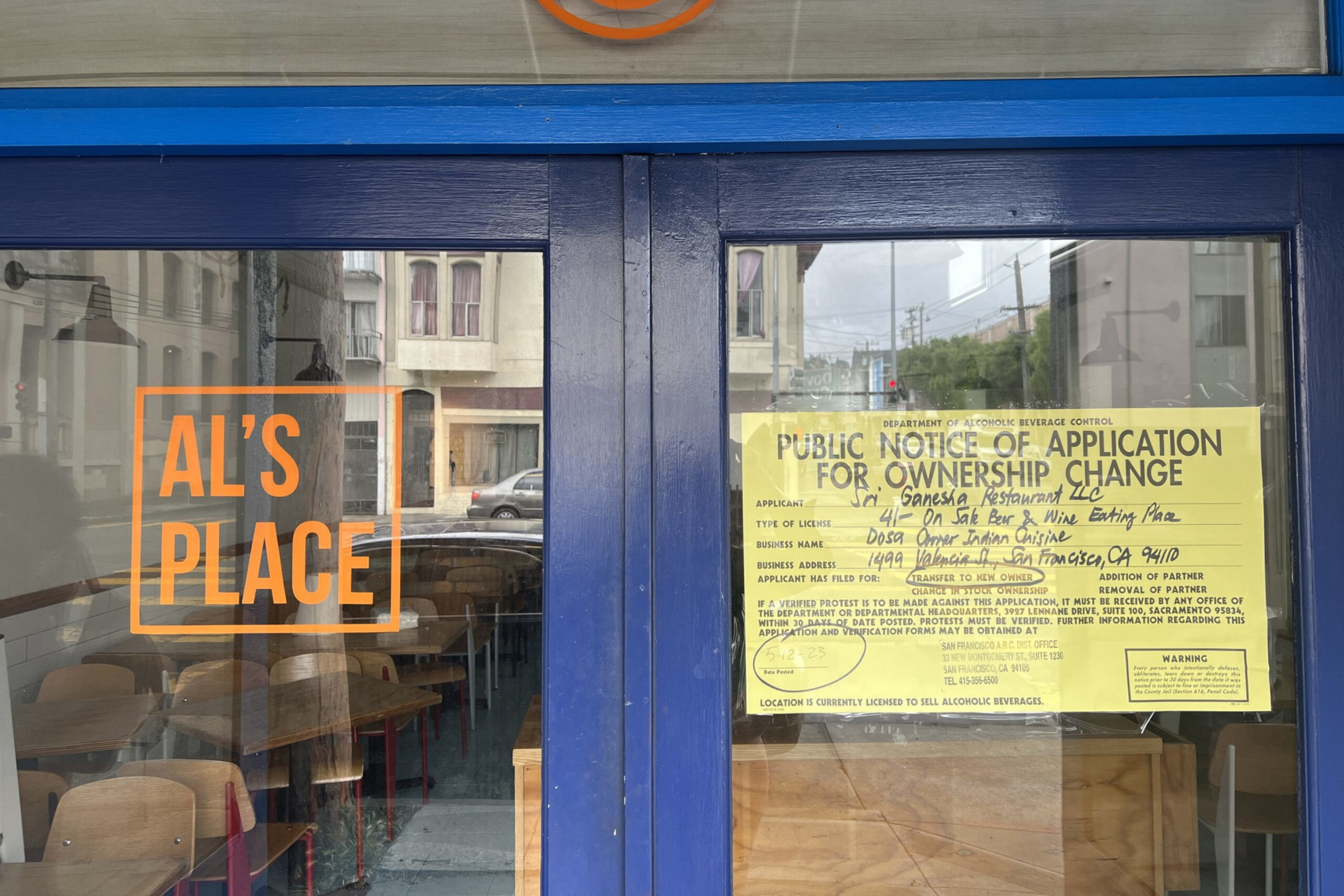 A blue double door has "AL'S PLACE" in orange letters on the left glass and a yellow public notice for a liquor license change on the right glass.