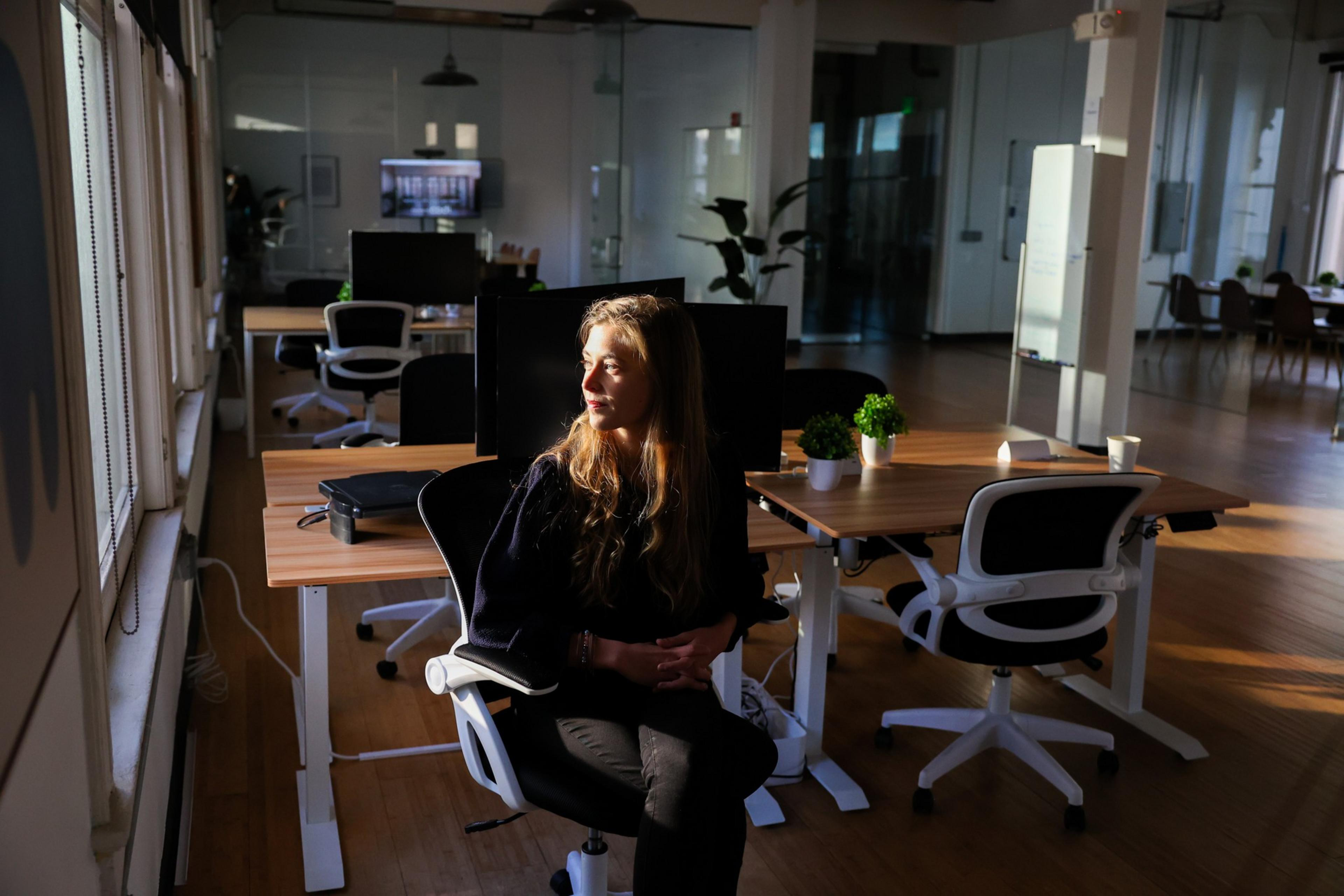 A person sits in an empty office looking out to the window as the sun comes in.