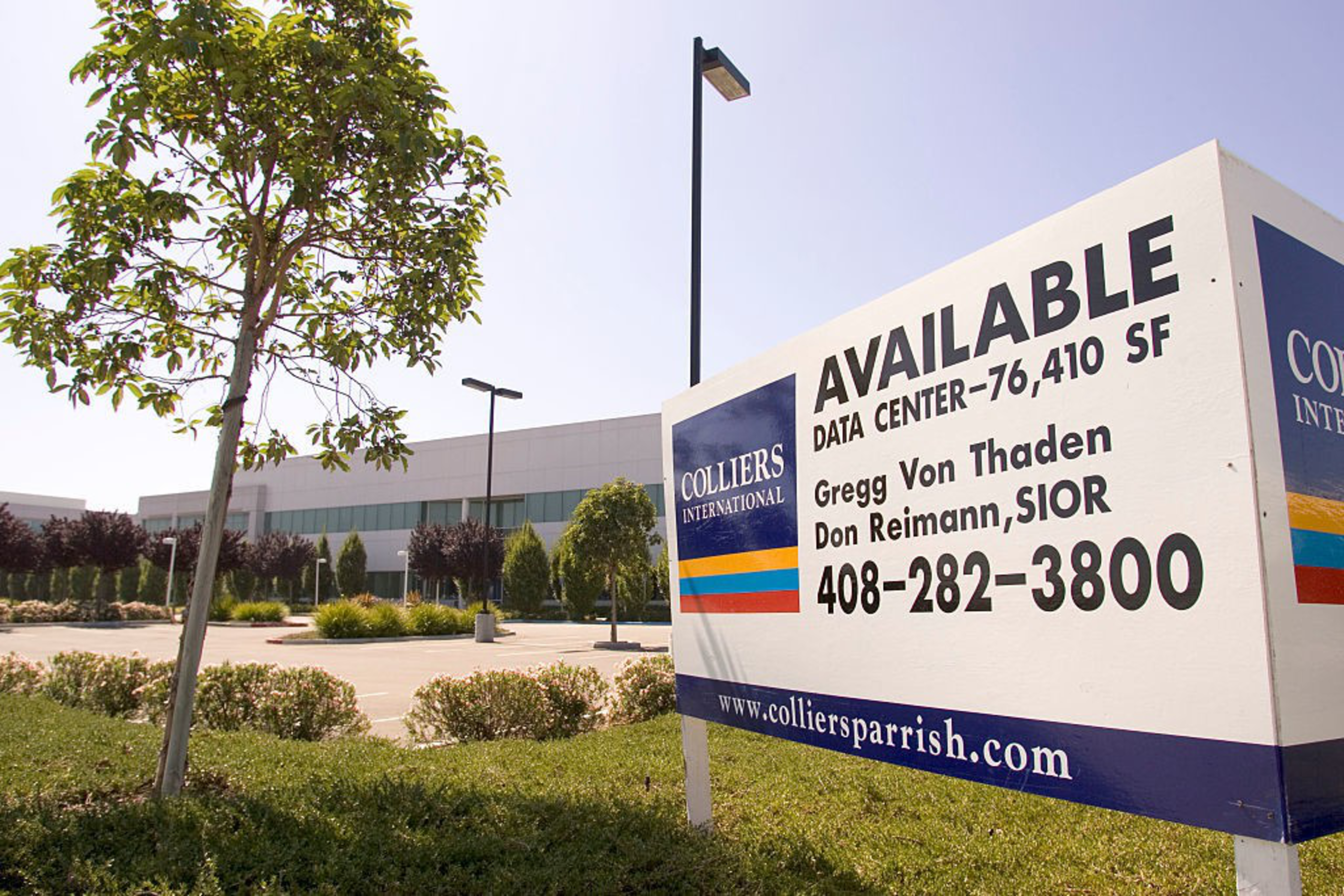A large sign advertises a 76,410 SF data center available, with contact details and Colliers International branding beside a modern office building.