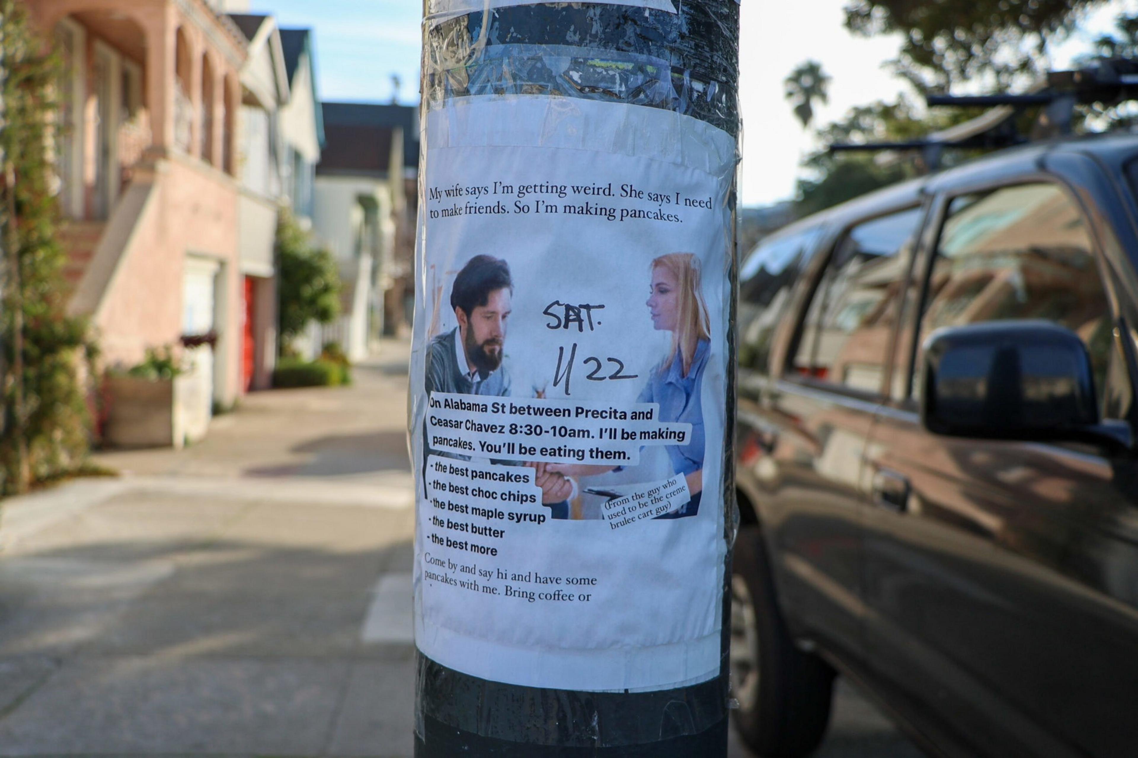 The image shows a humorous flyer on a pole inviting people to a pancake event on Alabama Street. It includes details about the time and menu, with a comedic touch.