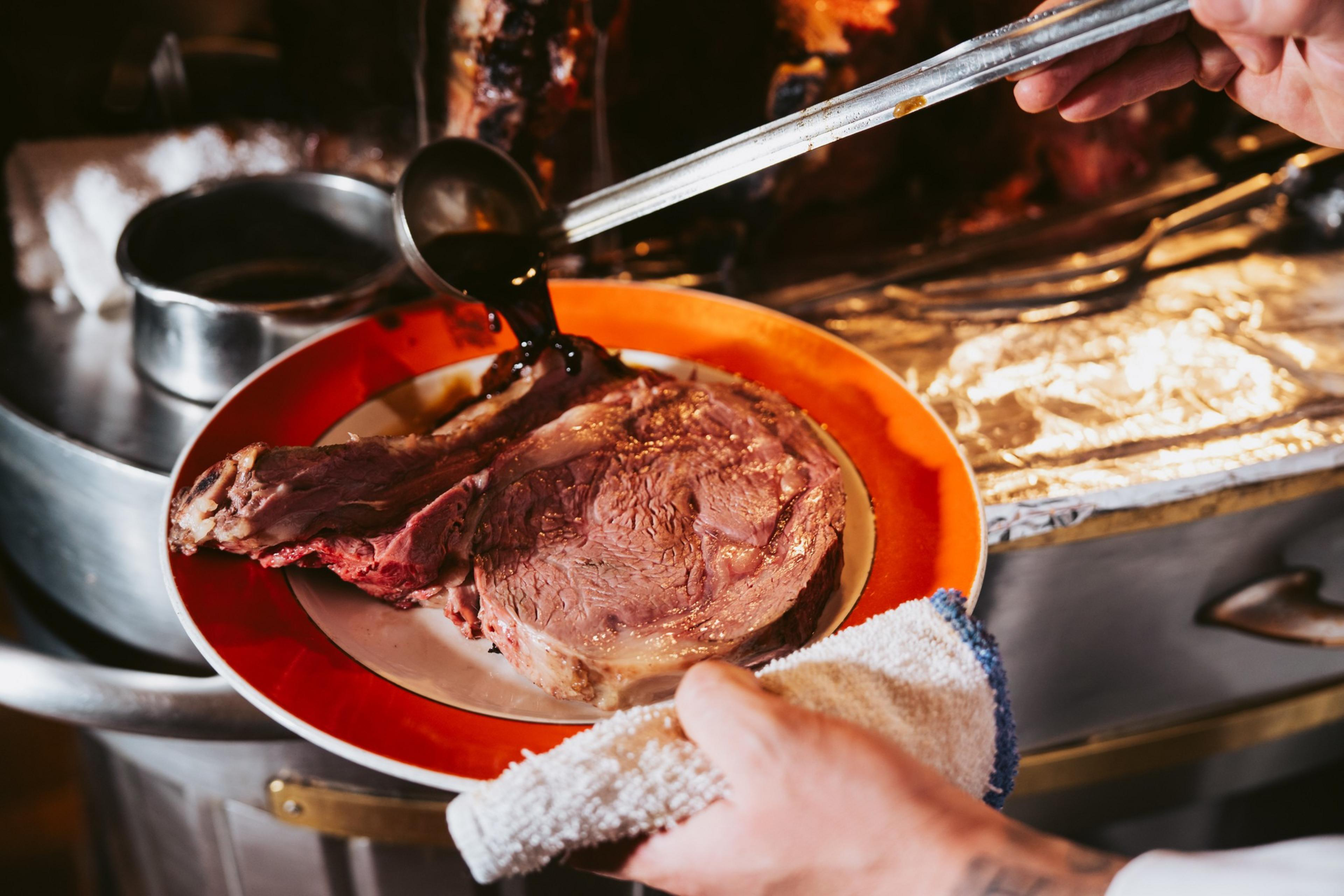 A server pours sauce tableside on to a steak at House of Prime Rib.