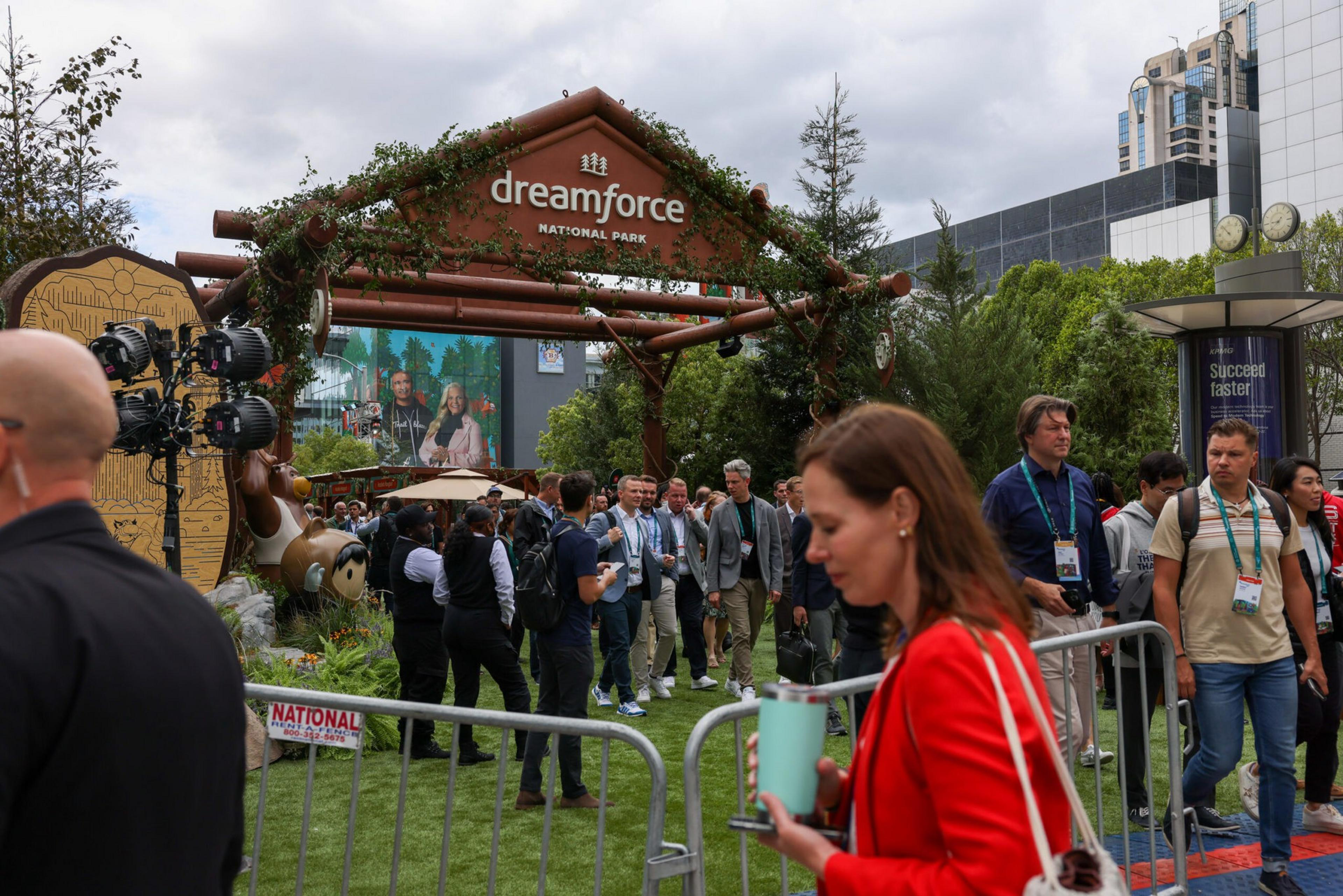 People gather under a large wooden archway decorated with greenery that reads "dreamforce NATIONAL PARK" at an outdoor event.