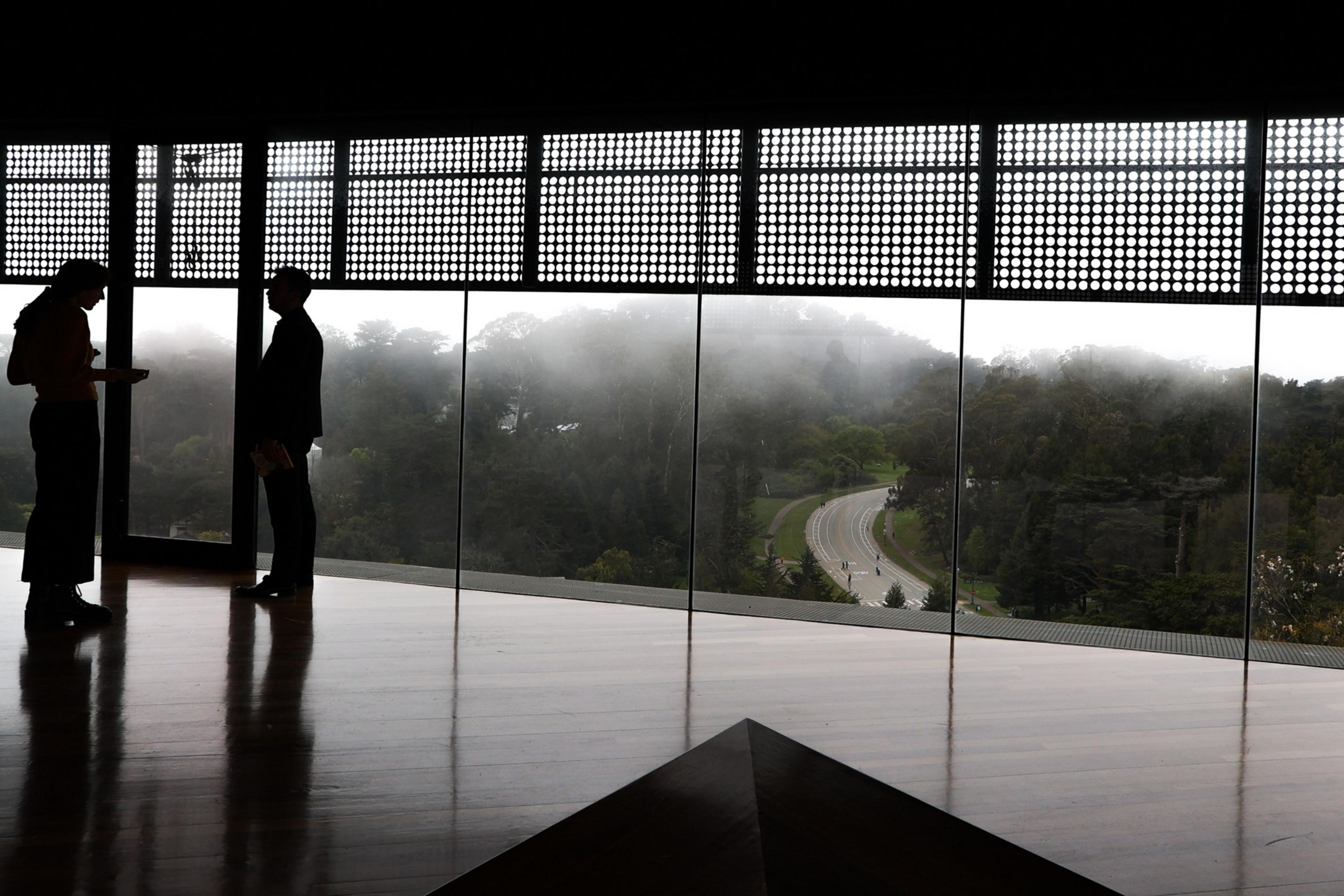 Two silhouettes stand in a tower as fog creeps in from the distance.