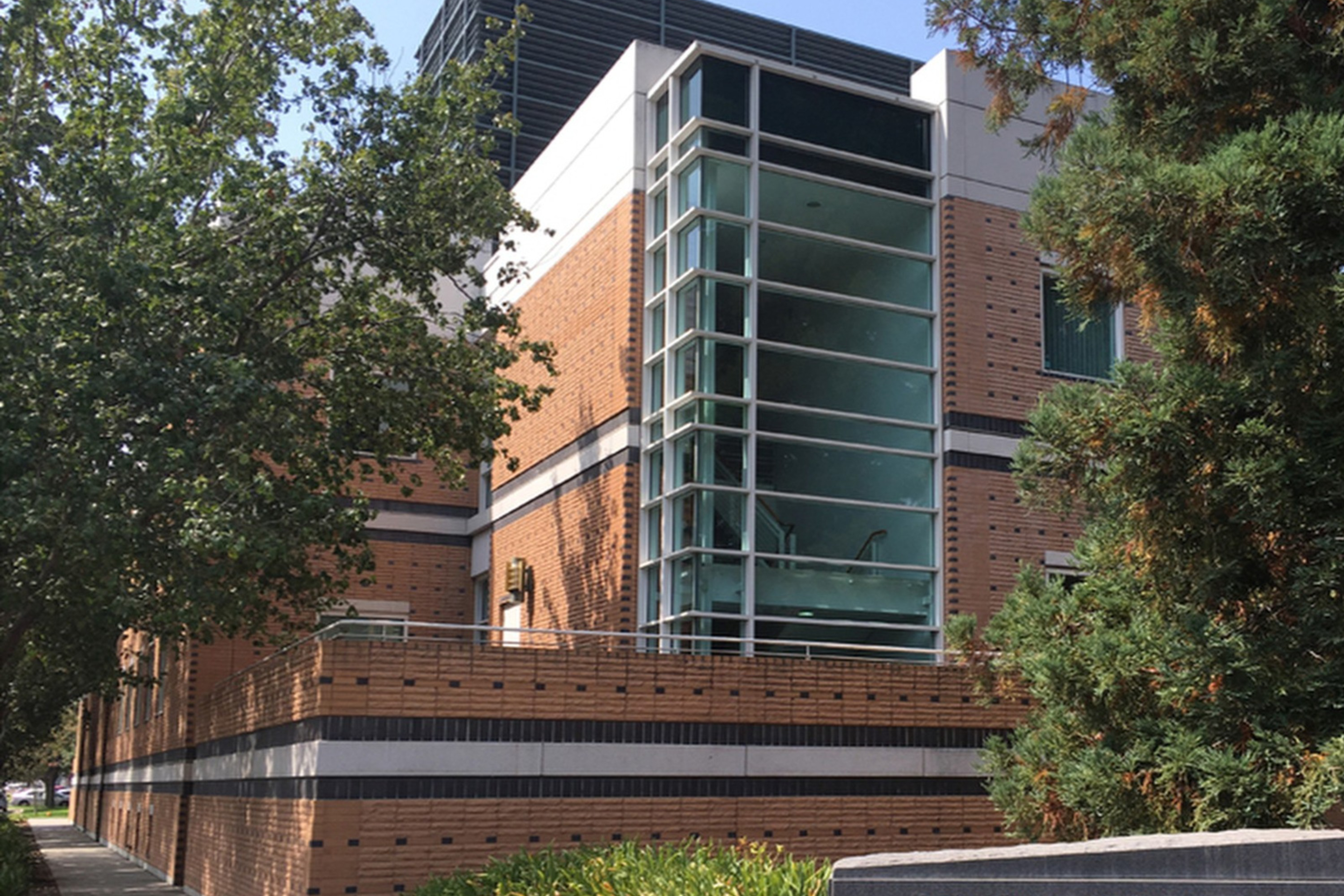 The image shows a brick building with large glass windows, surrounded by trees. A sign in front reads "U.S. Geological Survey, 345 Middlefield Road."
