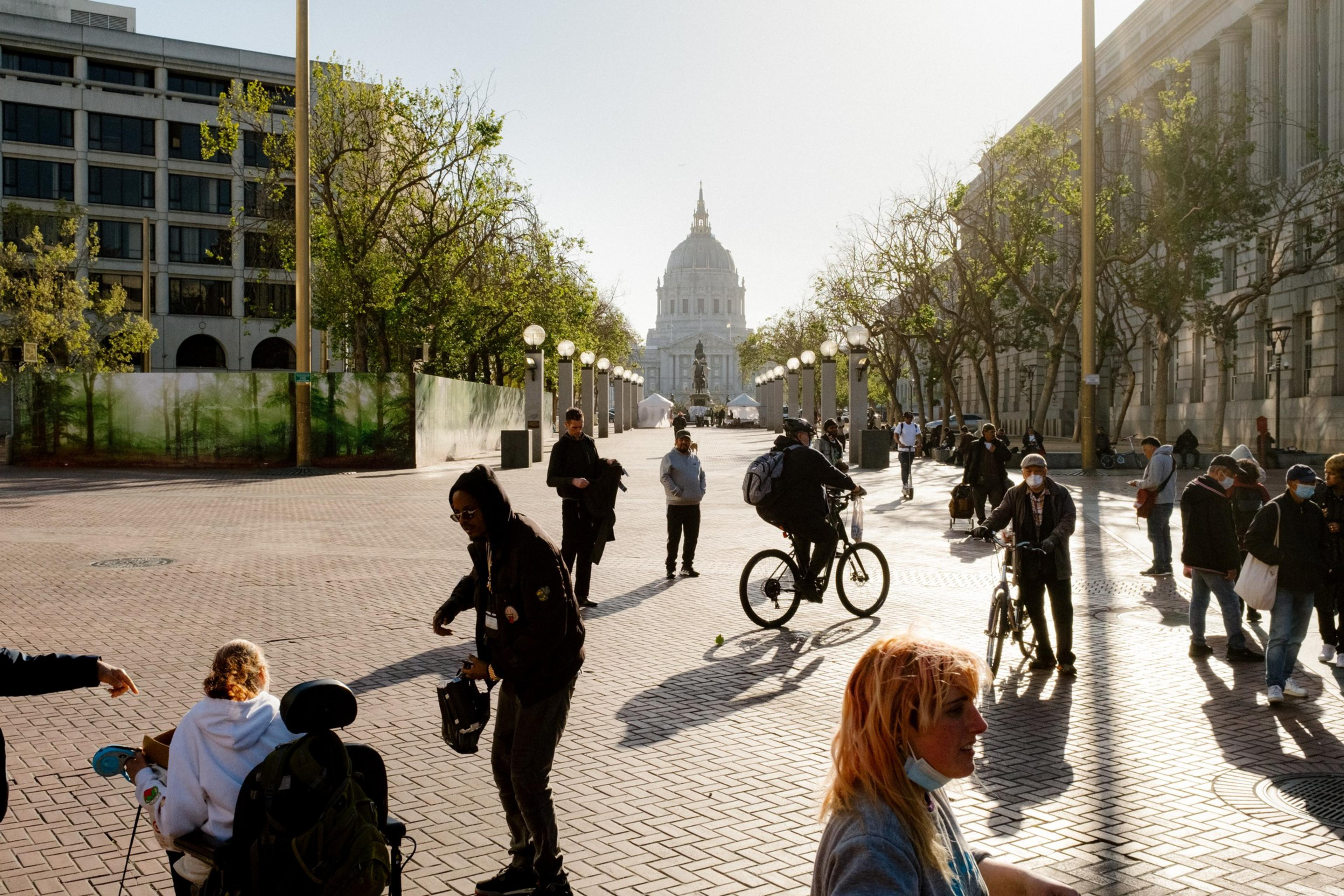 People stand around a plaza area with City Hall in the background.