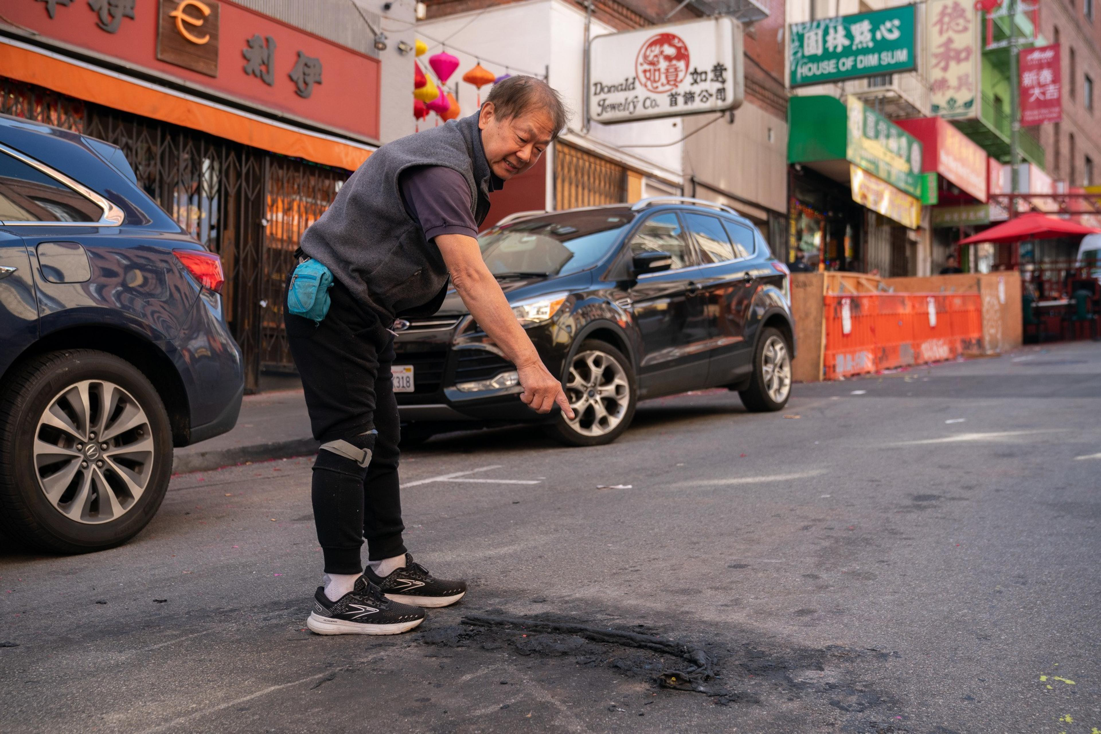 person points to charred remains in the street