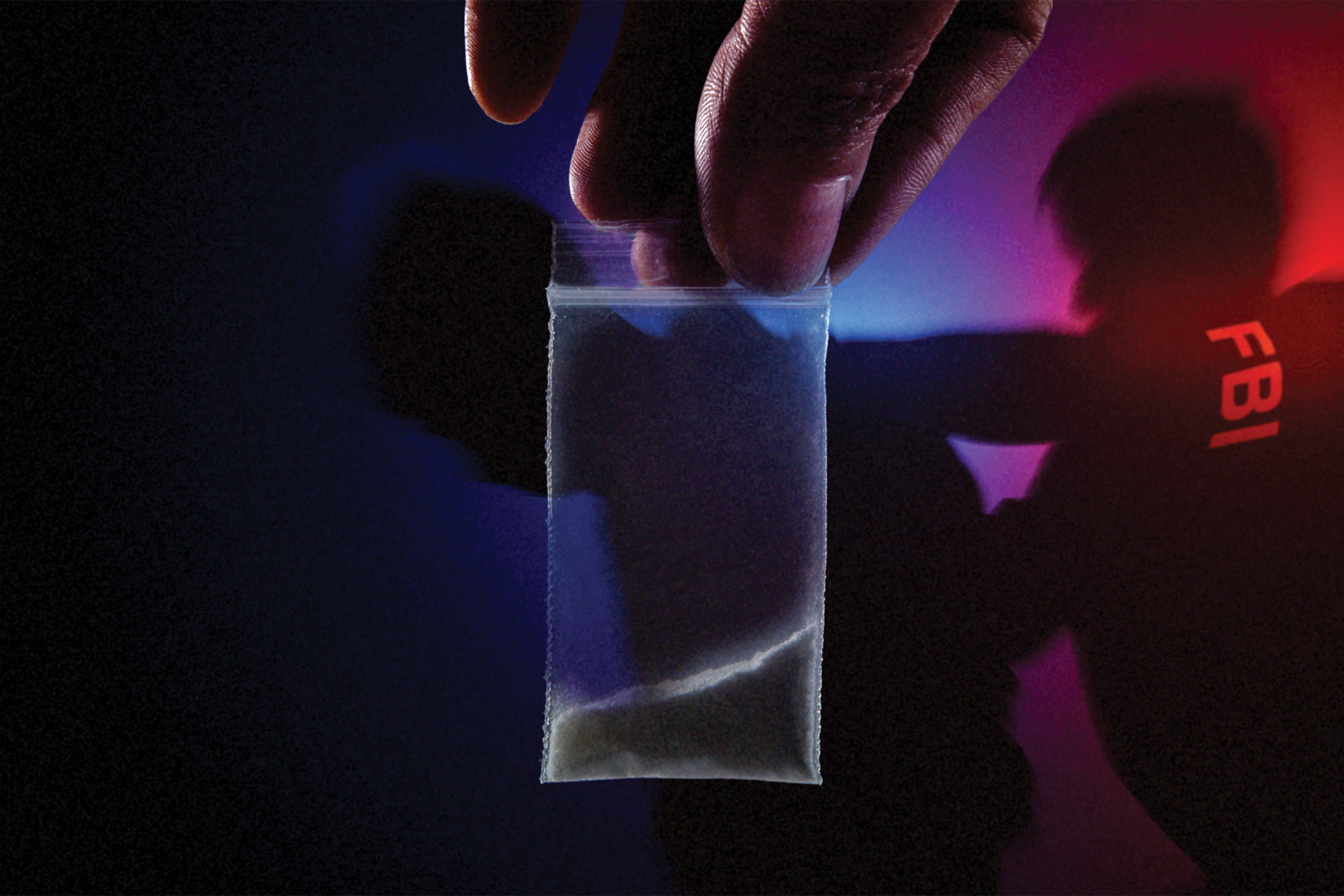 A hand holds a small clear plastic bag with white powder inside, while a shadowy figure wearing an FBI jacket is dimly visible in the background with red and blue lighting.