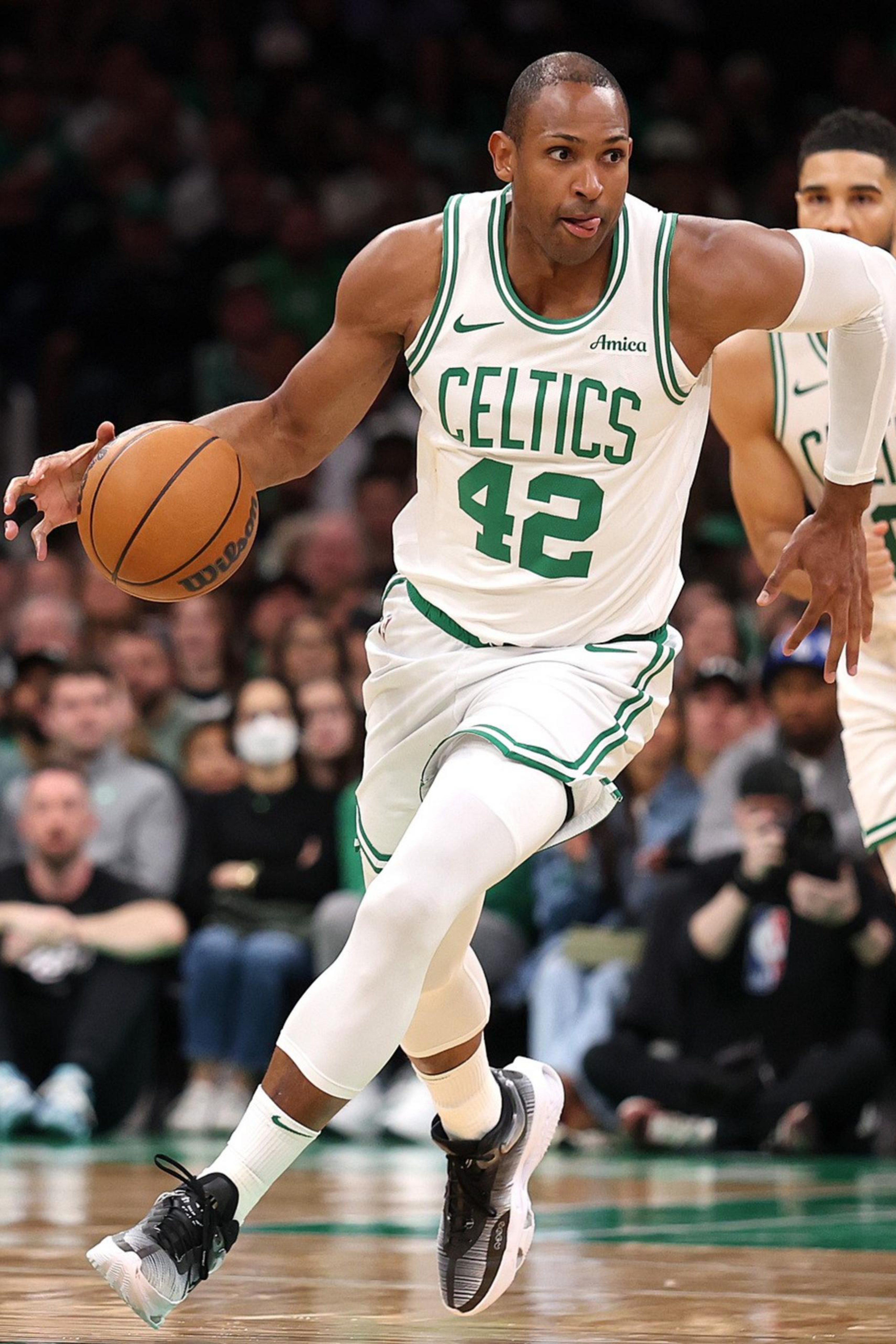 A Celtics player wearing jersey 42 dribbles the basketball while running, with another Celtics player wearing jersey 0 running behind him on the court.