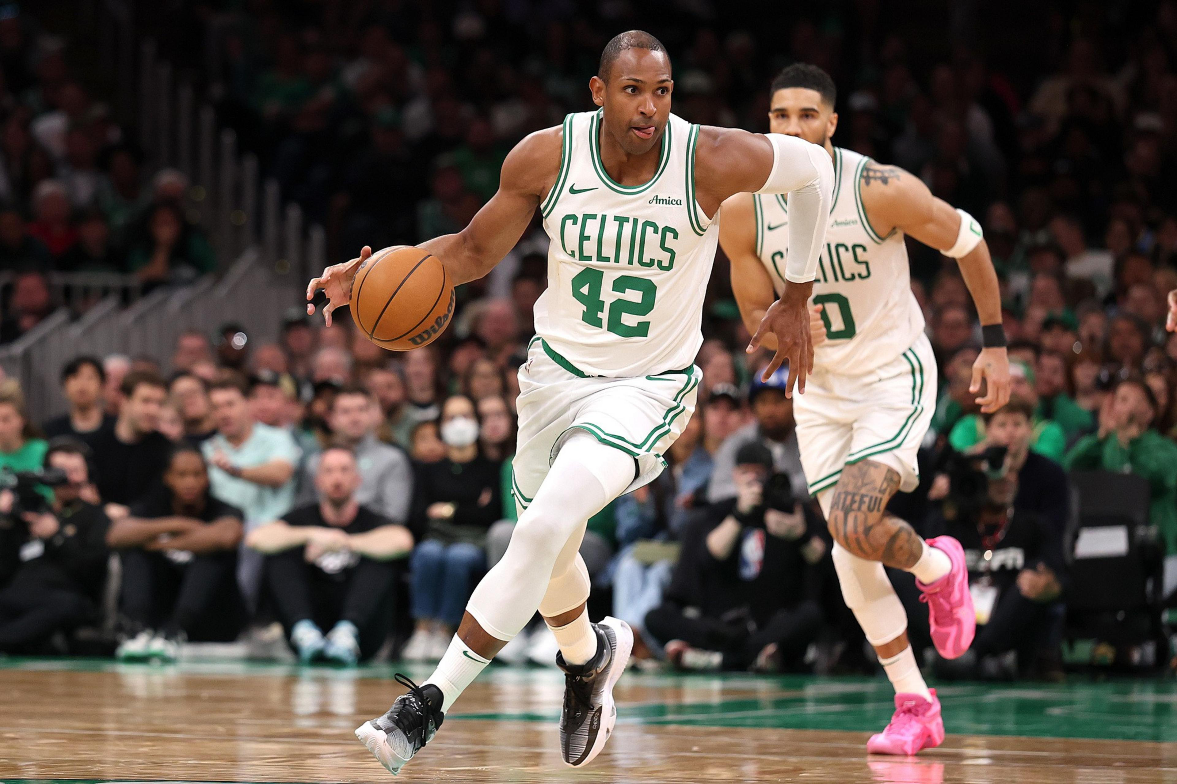 A Celtics player wearing jersey 42 dribbles the basketball while running, with another Celtics player wearing jersey 0 running behind him on the court.