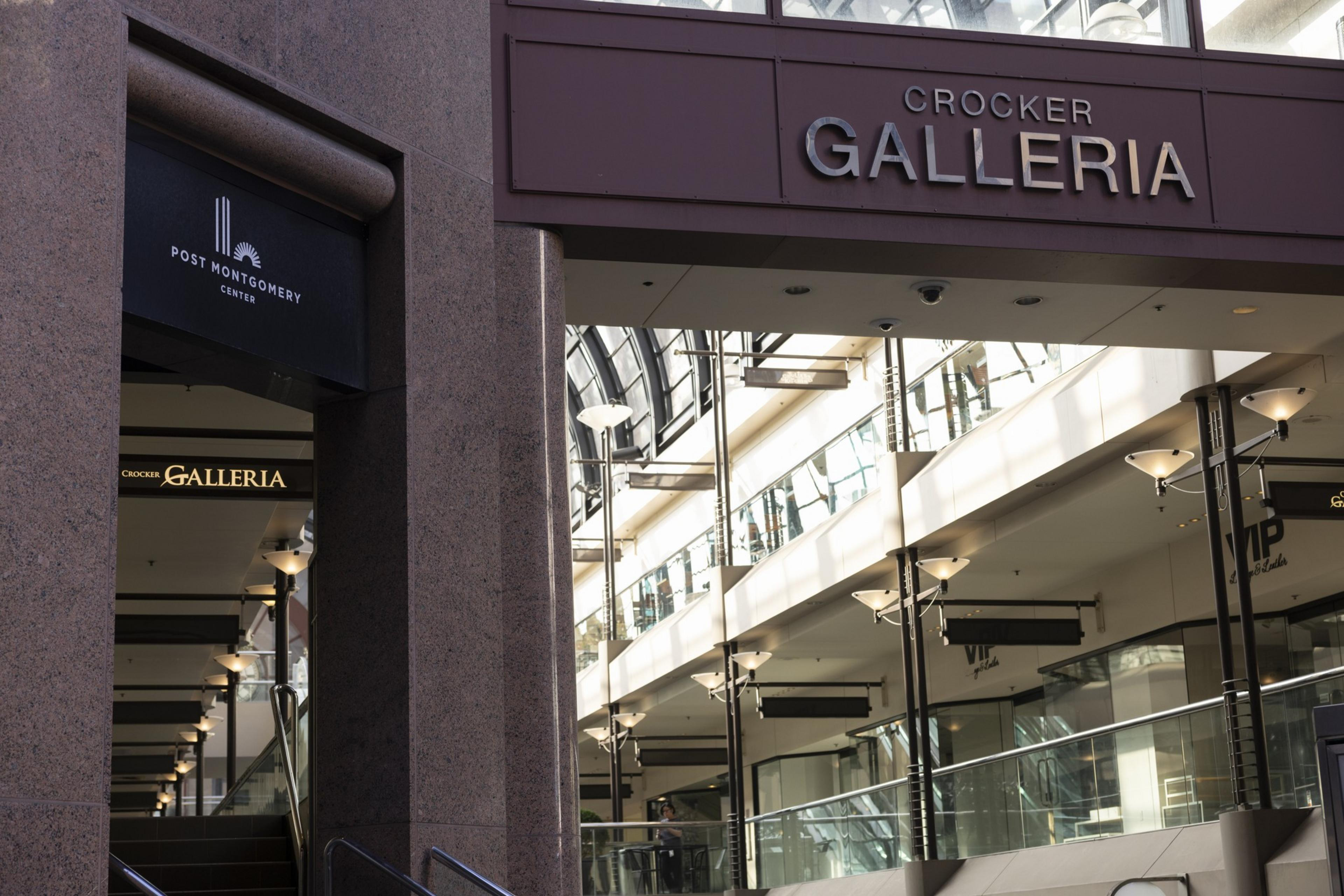 Entrance to Crocker Galleria in a building with glass ceilings, multiple floors, and modern lamps along the walkways.
