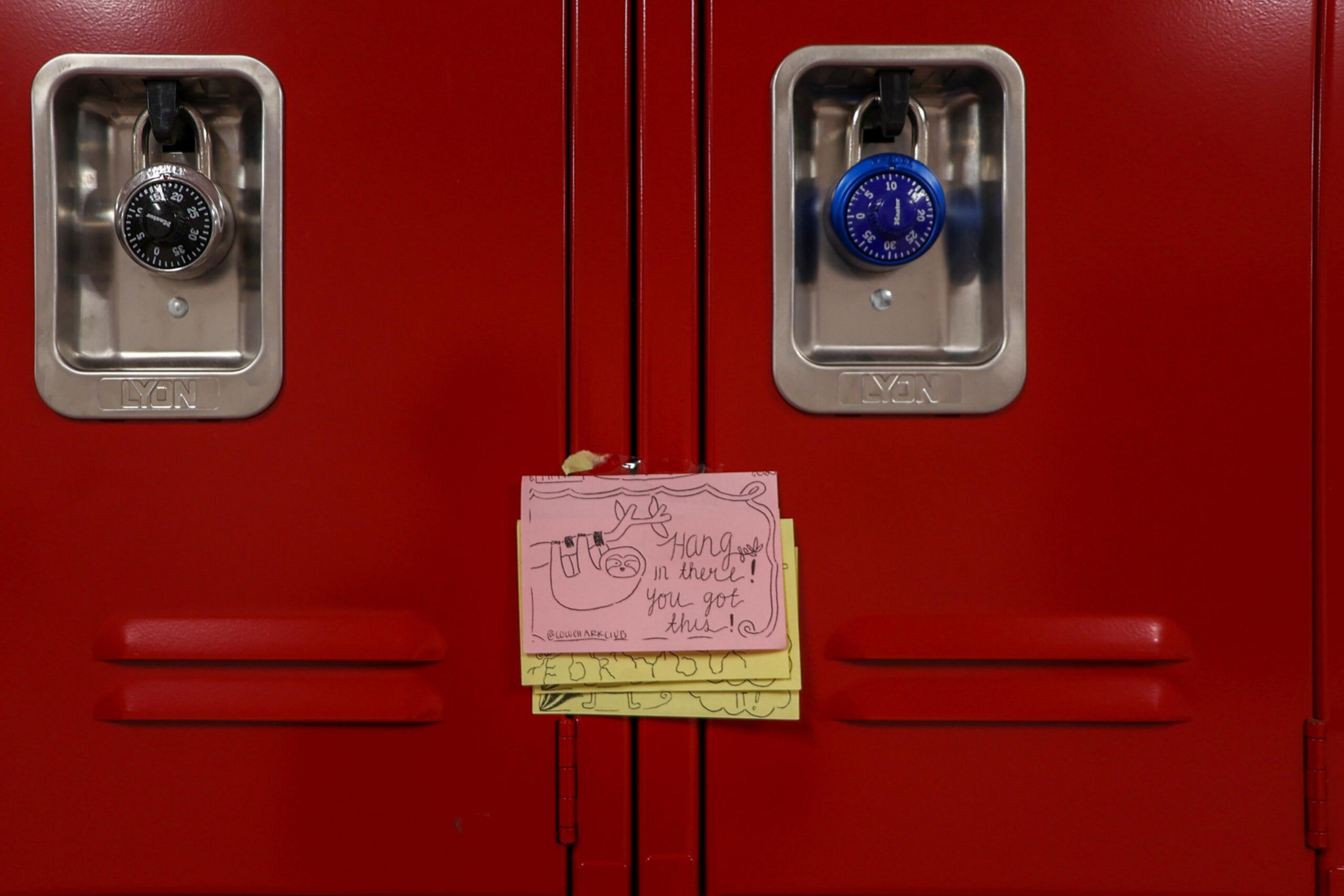 Two red lockers with black and blue combination locks have colorful sticky notes attached, one reading "Hang in there! You got this!"