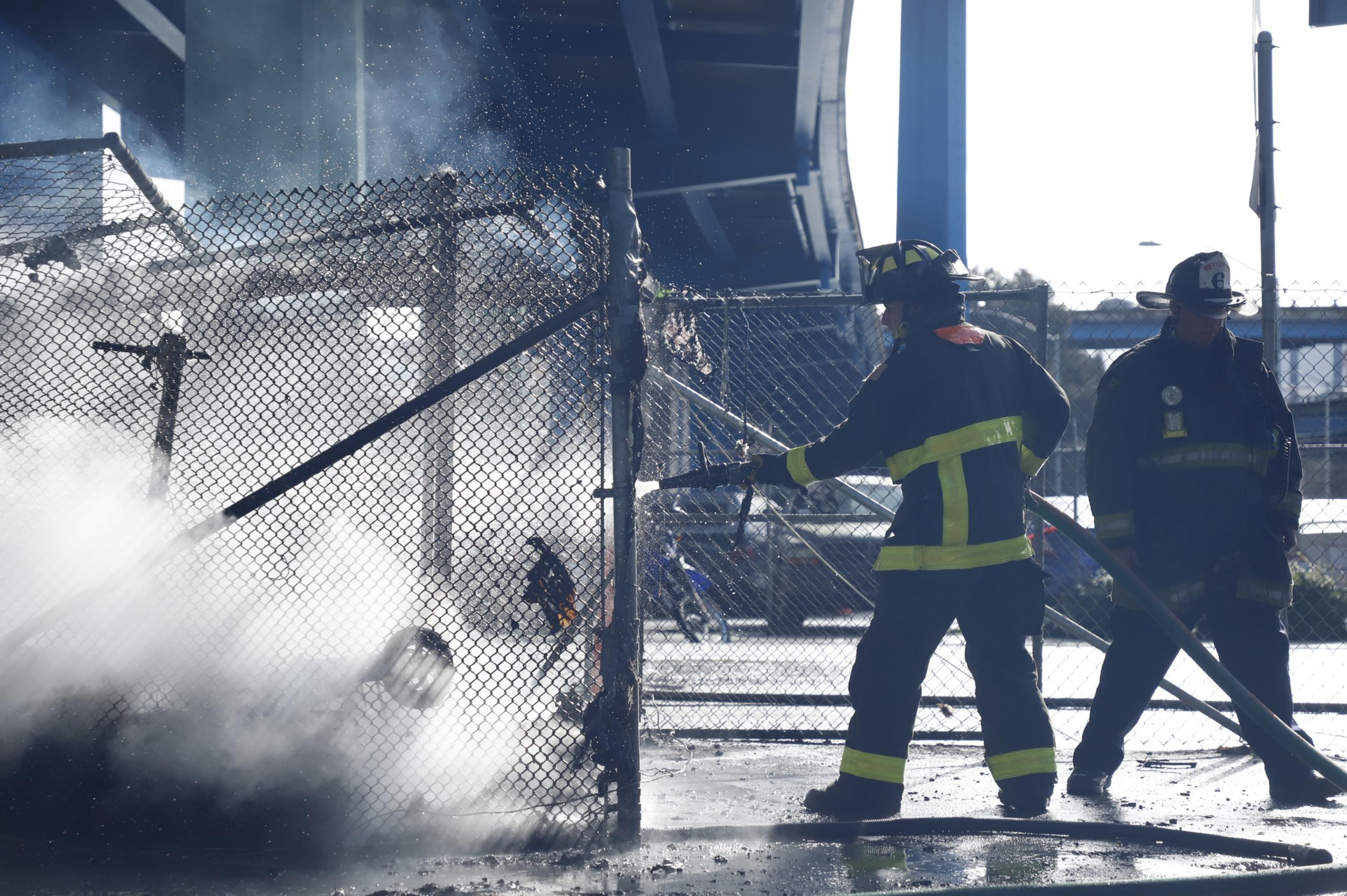 SFFD firefighters spray water on an active fire in a homeless encampment on Division Street.