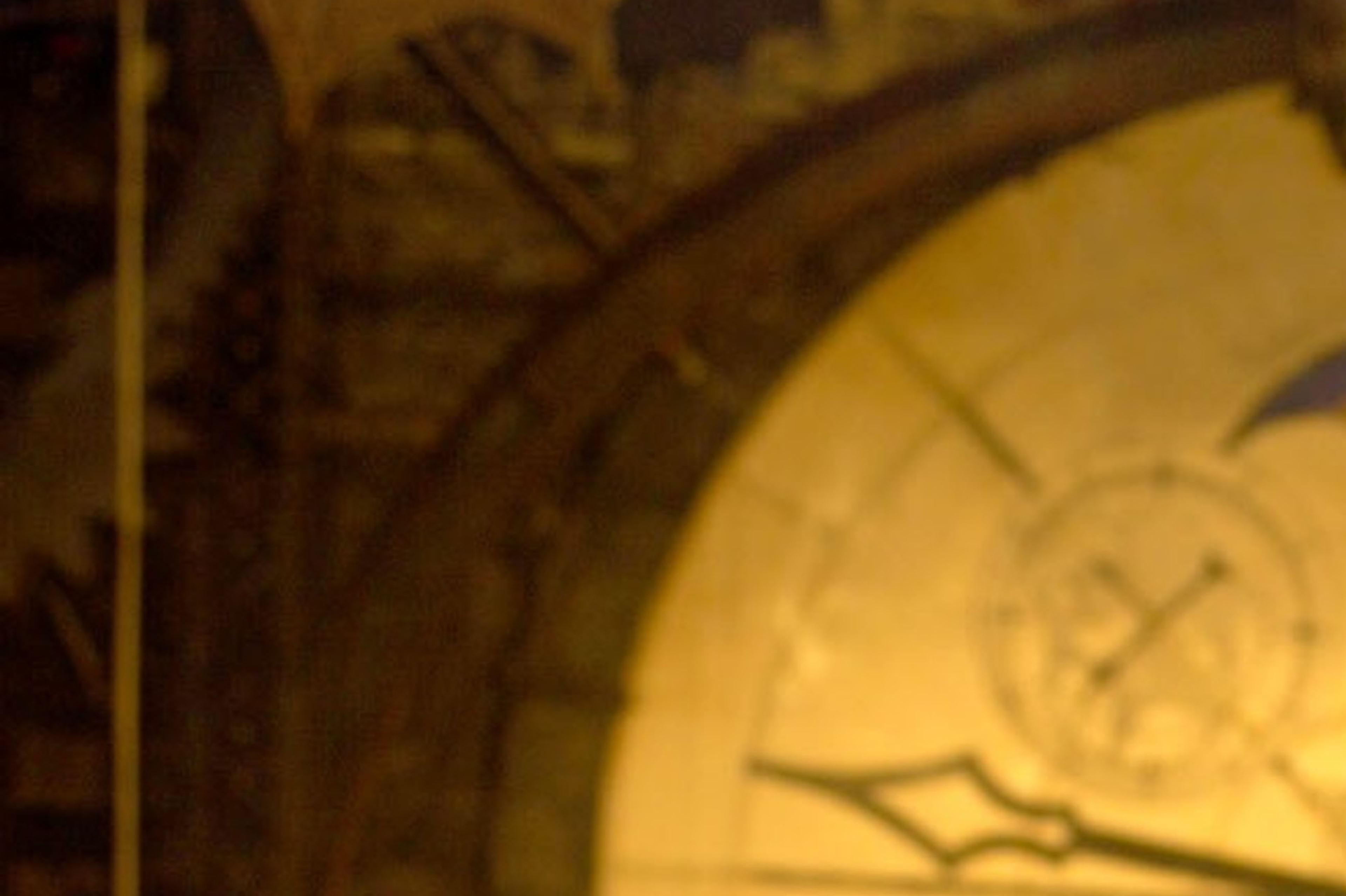 Two women stand smiling in front of a theater stage with a large clock and dragon decoration above. The ambience suggests a set for a theatrical production.