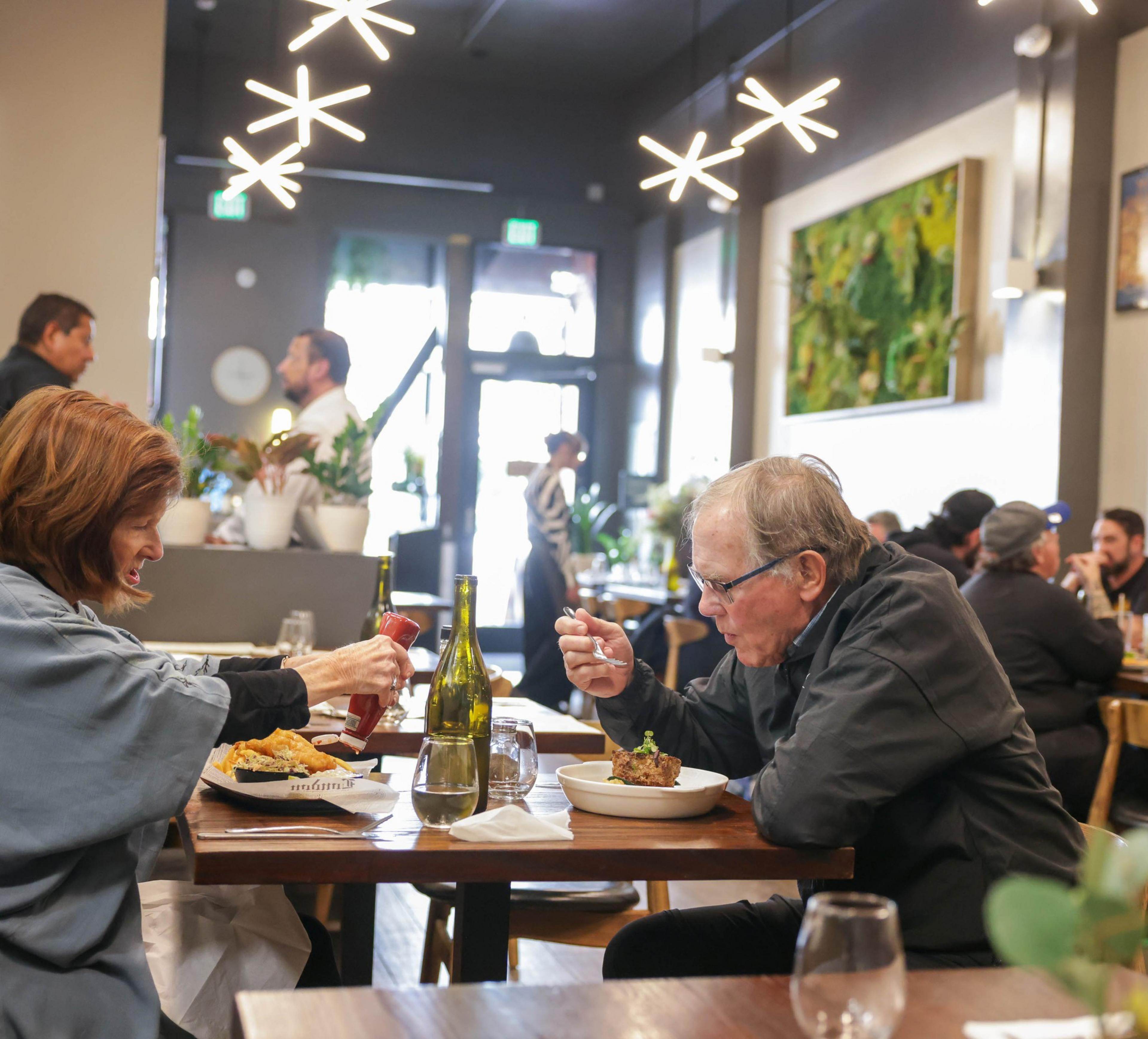 A couple dining in a bustling restaurant with modern decor and star-shaped lights.