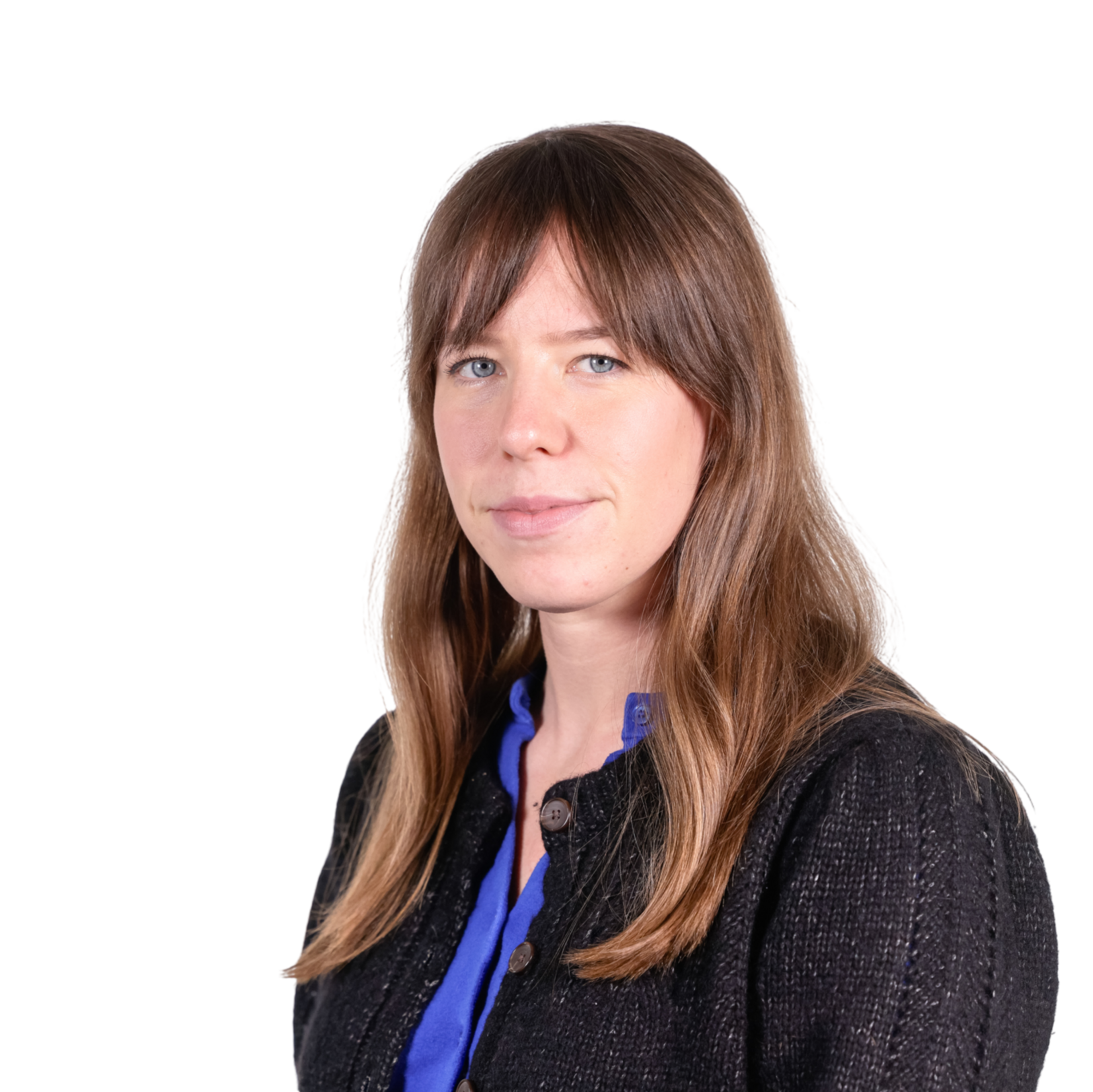 A woman with long brown hair wearing a blue top and a black textured jacket looks calmly at the camera against a plain background.