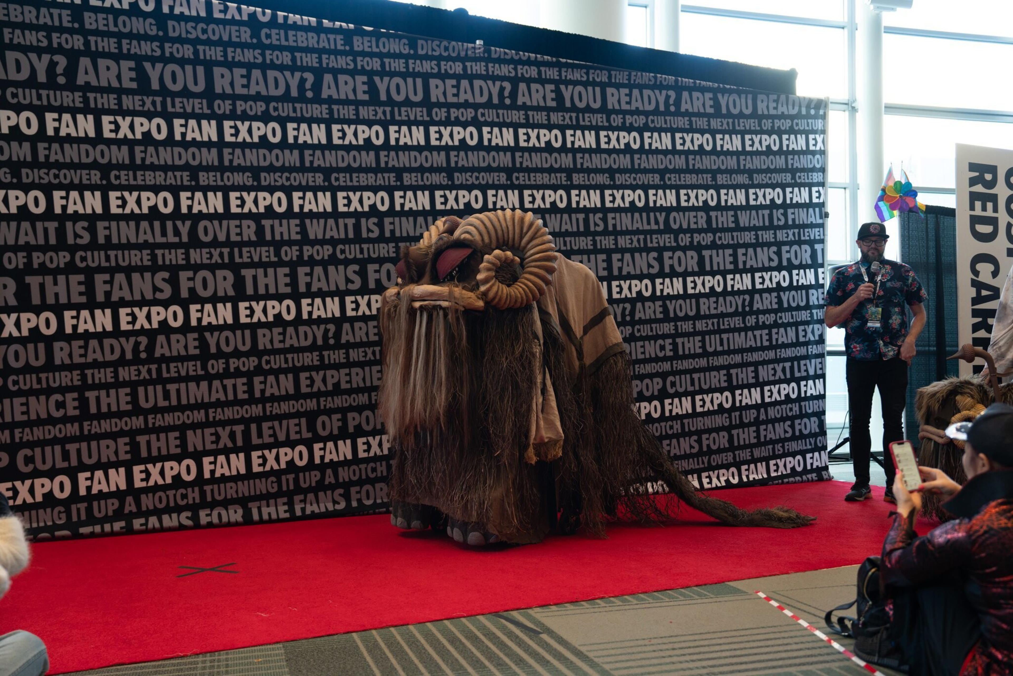 a large alien costume is in front of a step-and-repeat.