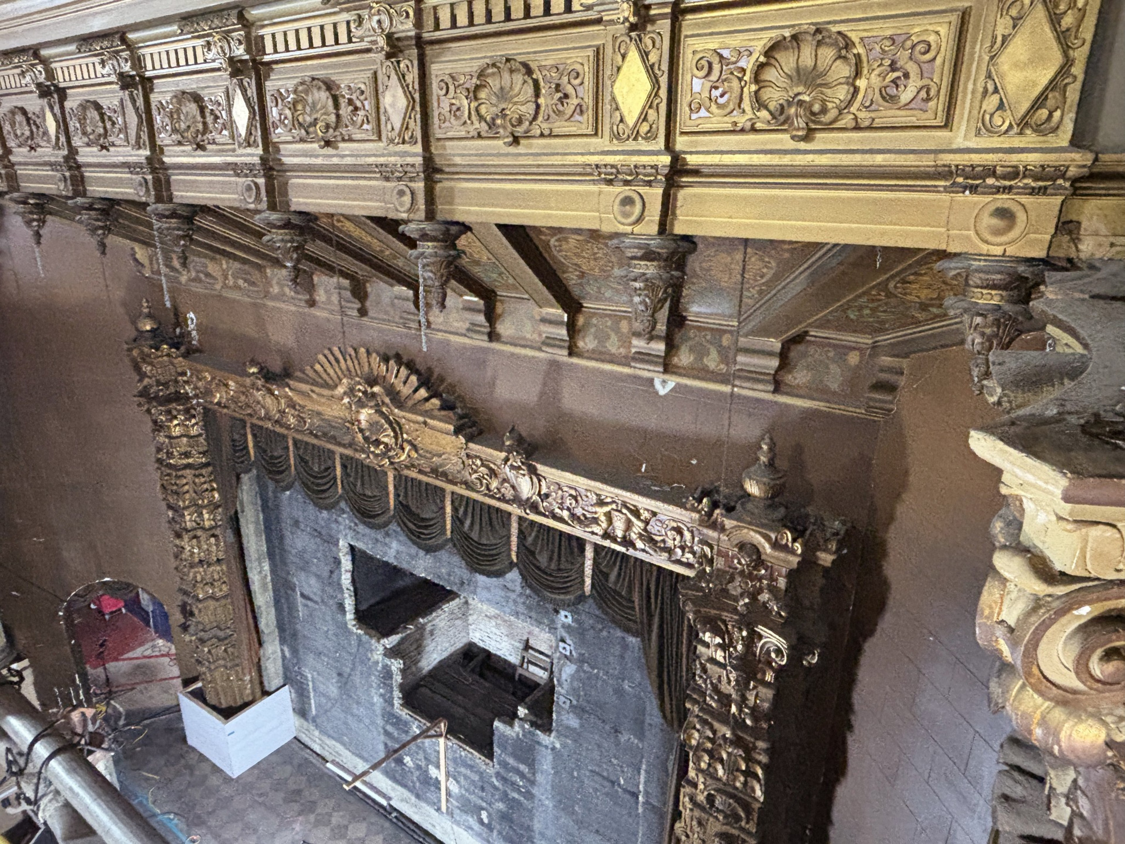 a view from above shows an elaborate, gold-painted square arch framing a movie theater stage, with its screen having been removed