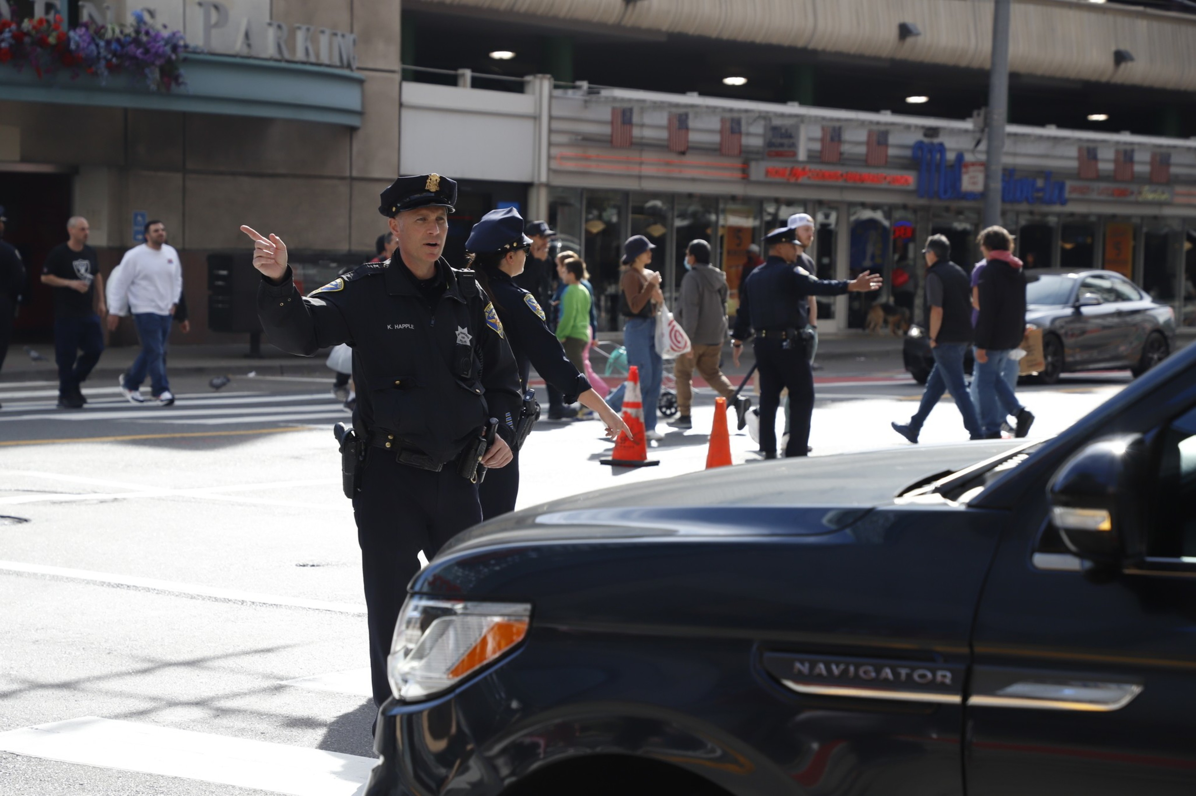 Three SFPD officers stand in the middle of the street forcing traffic to detour.
