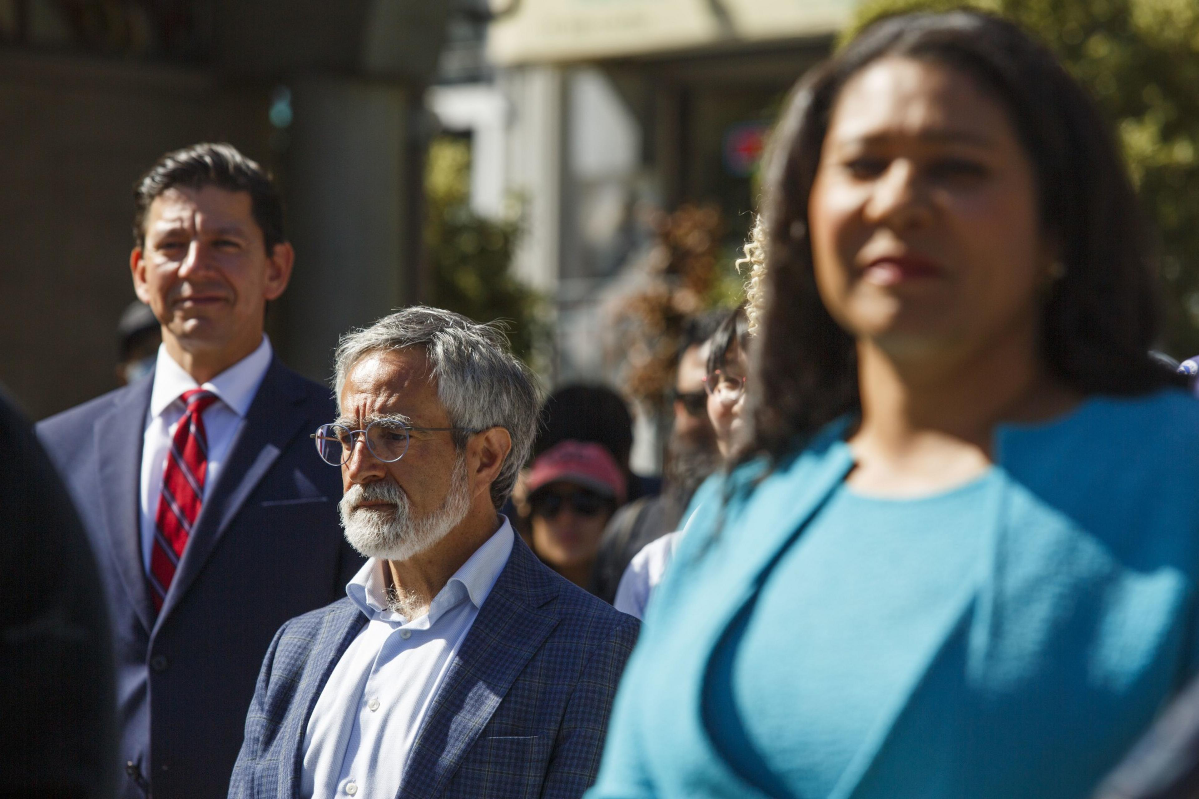 A diverse group of people in professional attire, focusing on something out of frame.