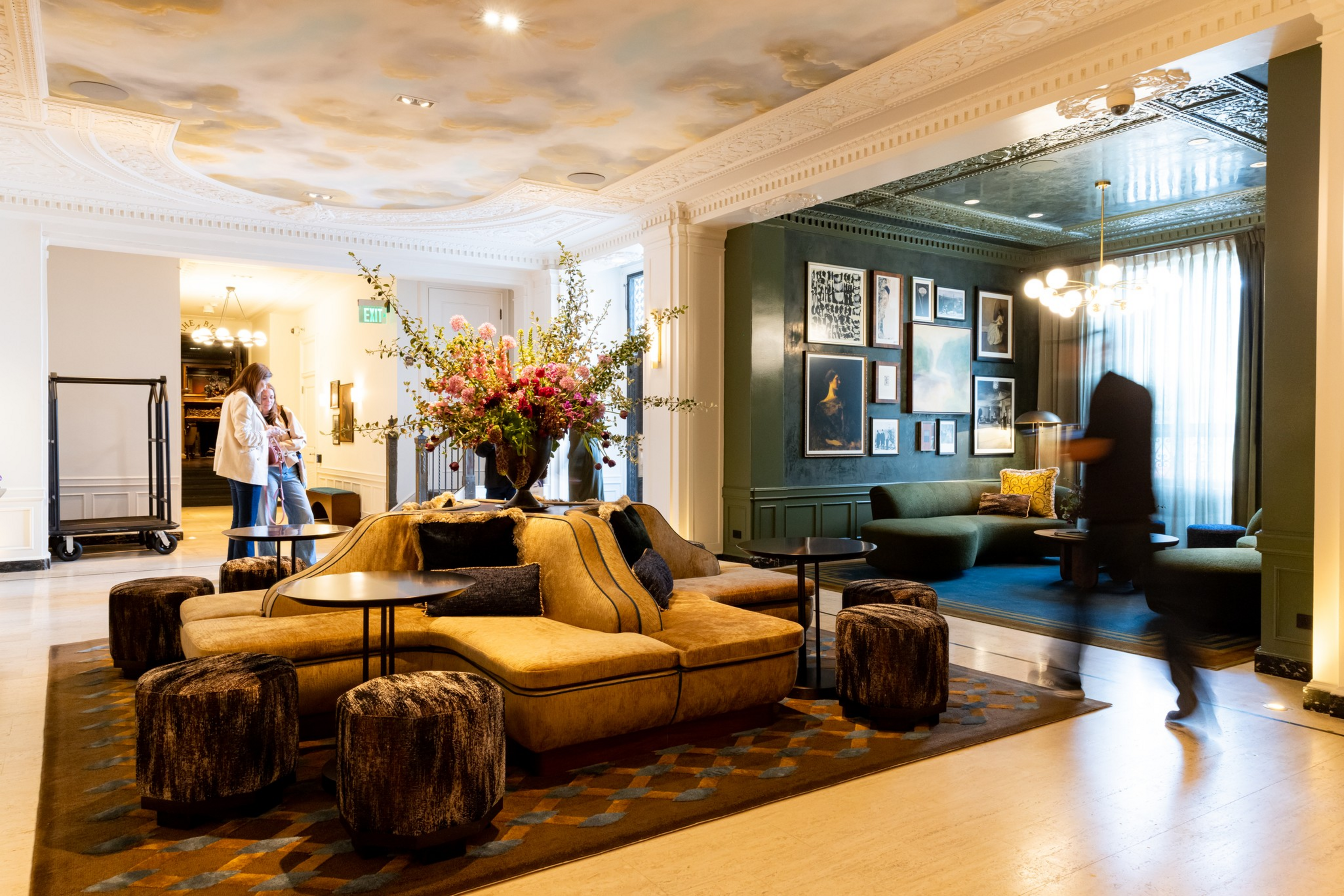 A luxurious lounge area features a central tan sofa with black cushions ...