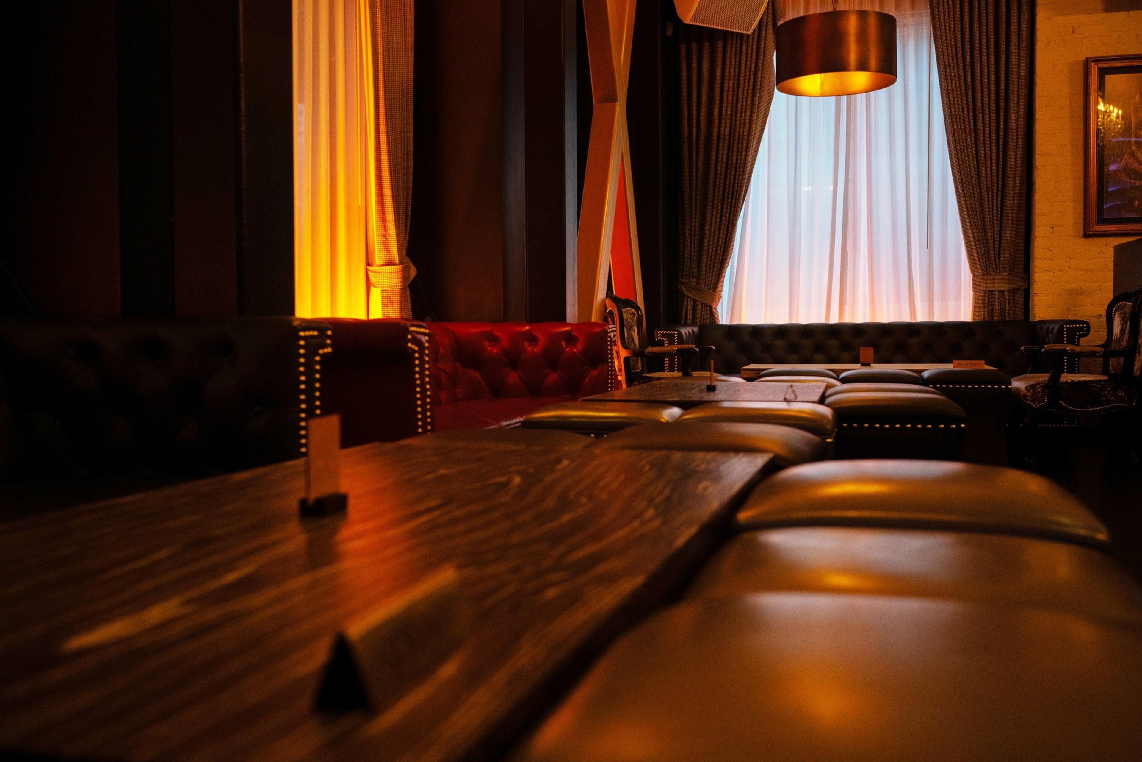 An empty, lowly lit lounge area with large curtain in the background.