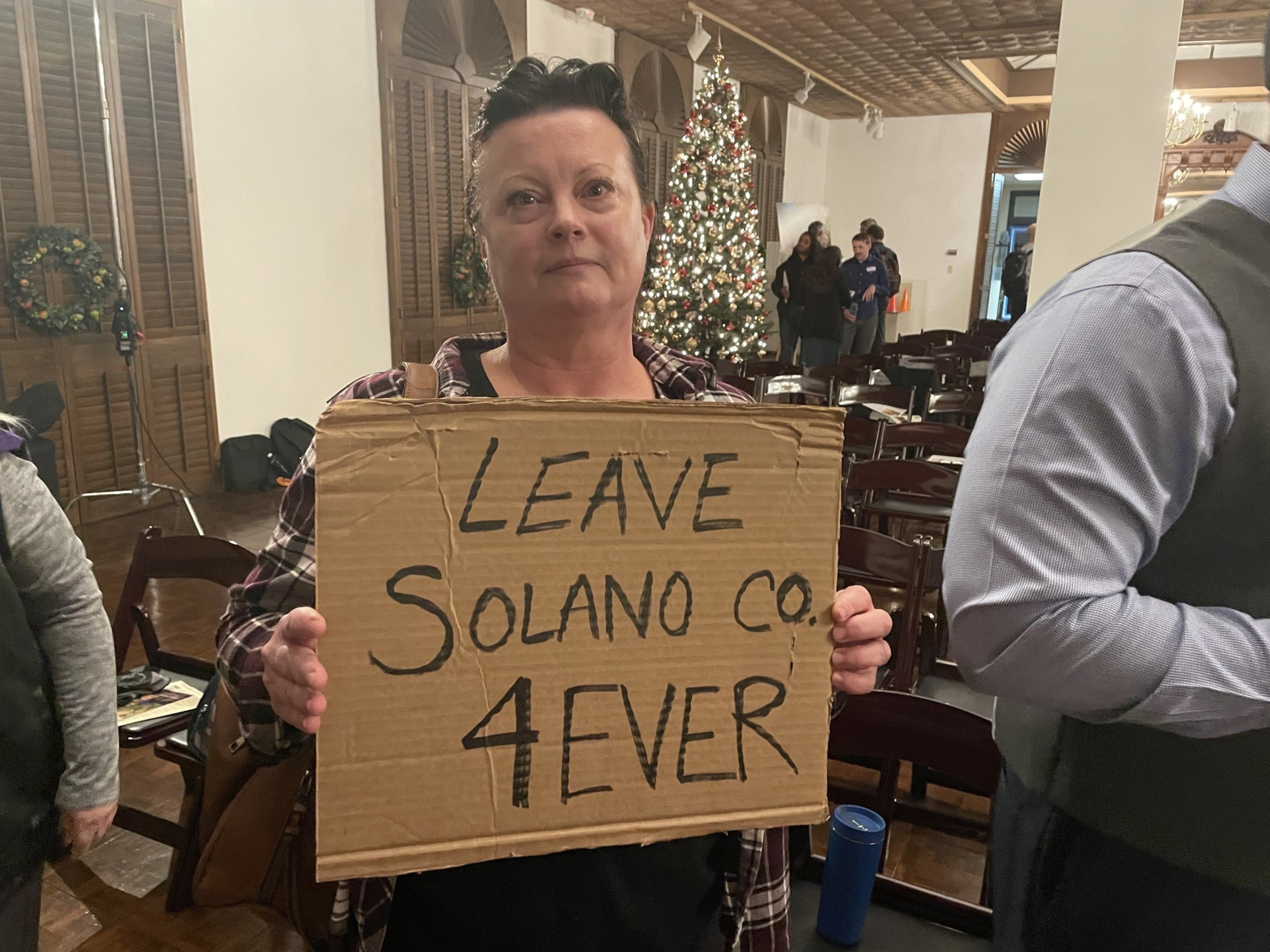 A woman holds up a cardboard sign.
