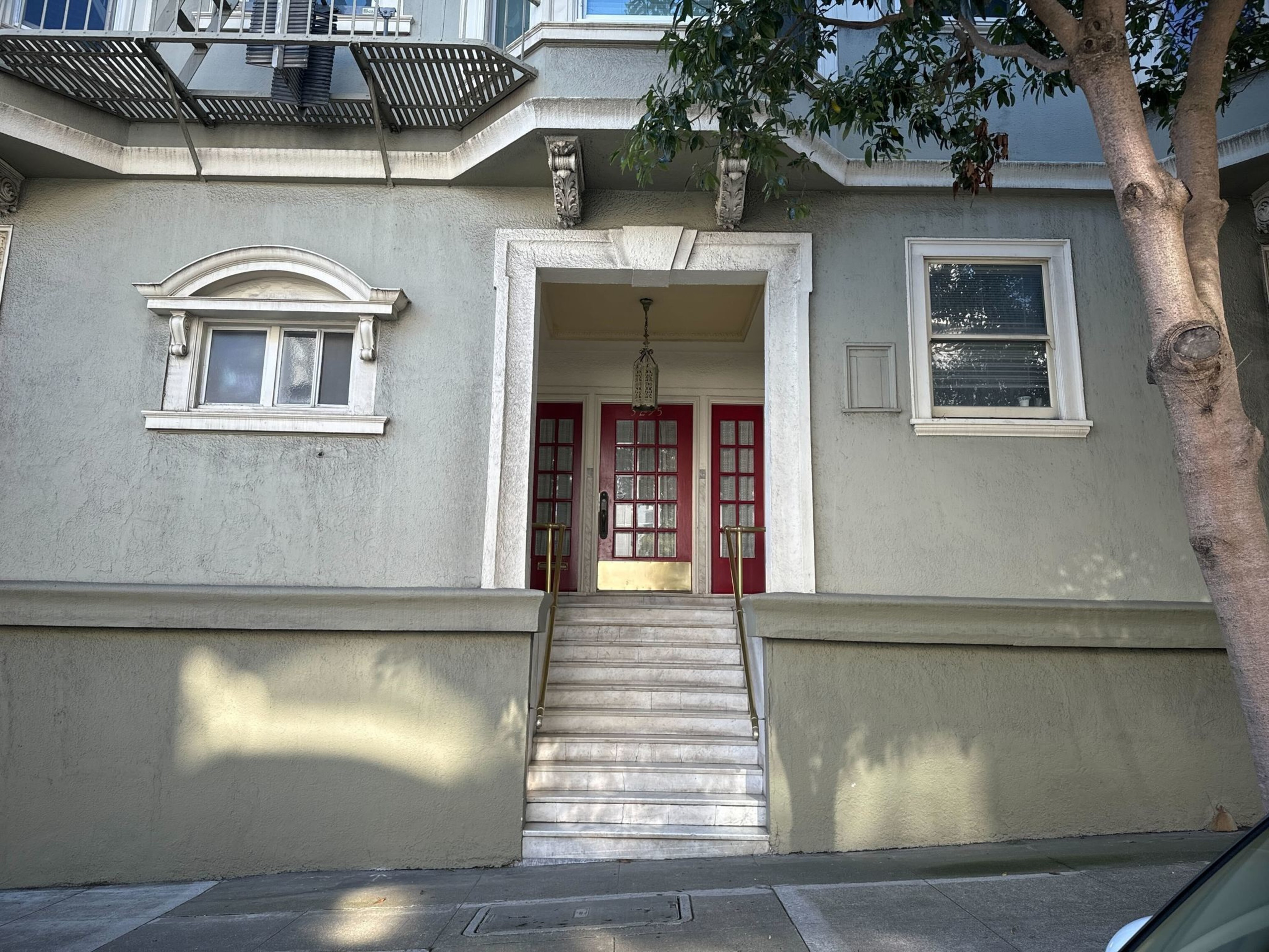 a red door to an apartment building i seen behind steps