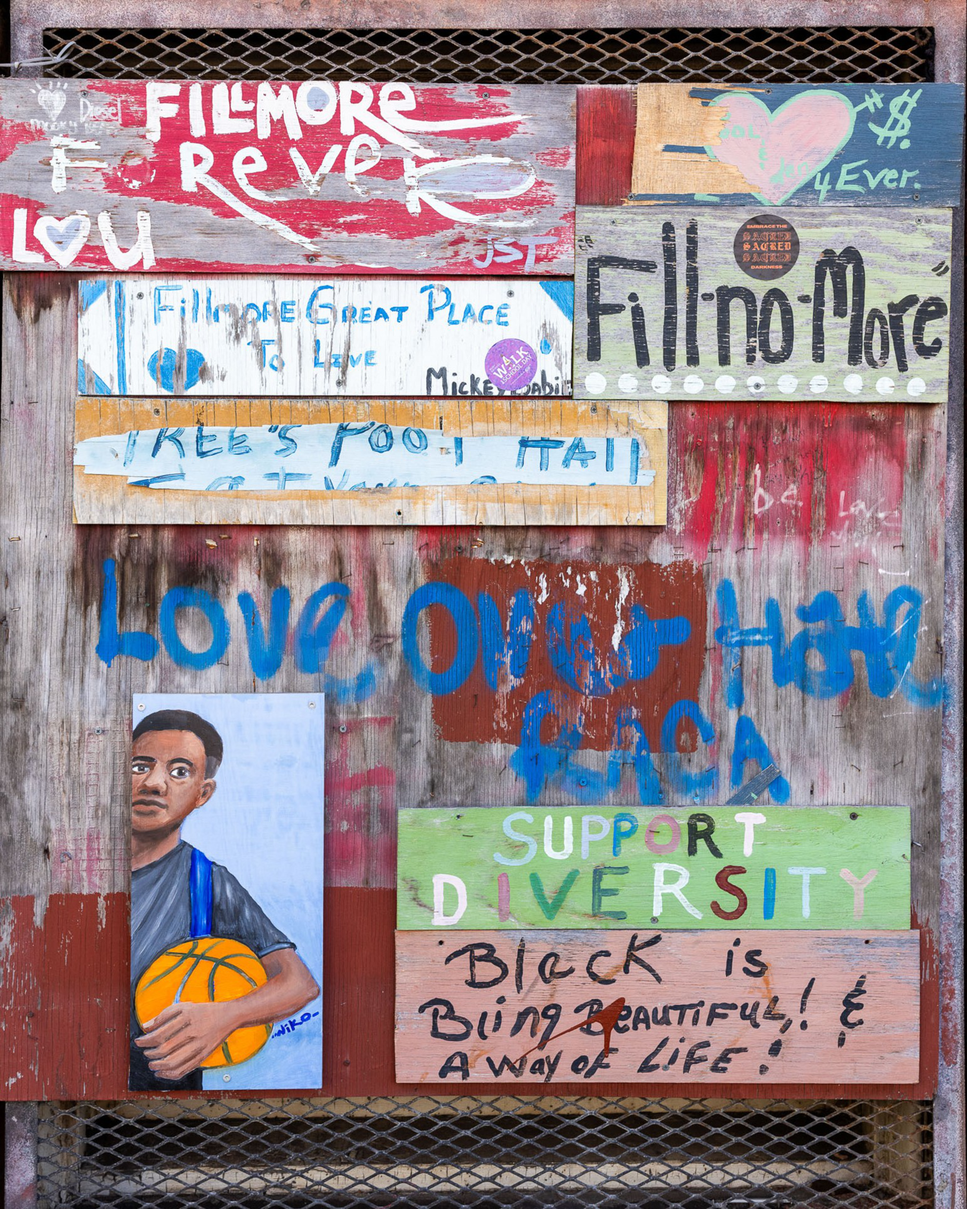 The image shows a collage of colorful, hand-painted signs with messages like &quot;Fillmore 4ever,&quot; &quot;Support Diversity,&quot; and &quot;Black is beautiful!&quot; near a painting of a boy with a basketball.