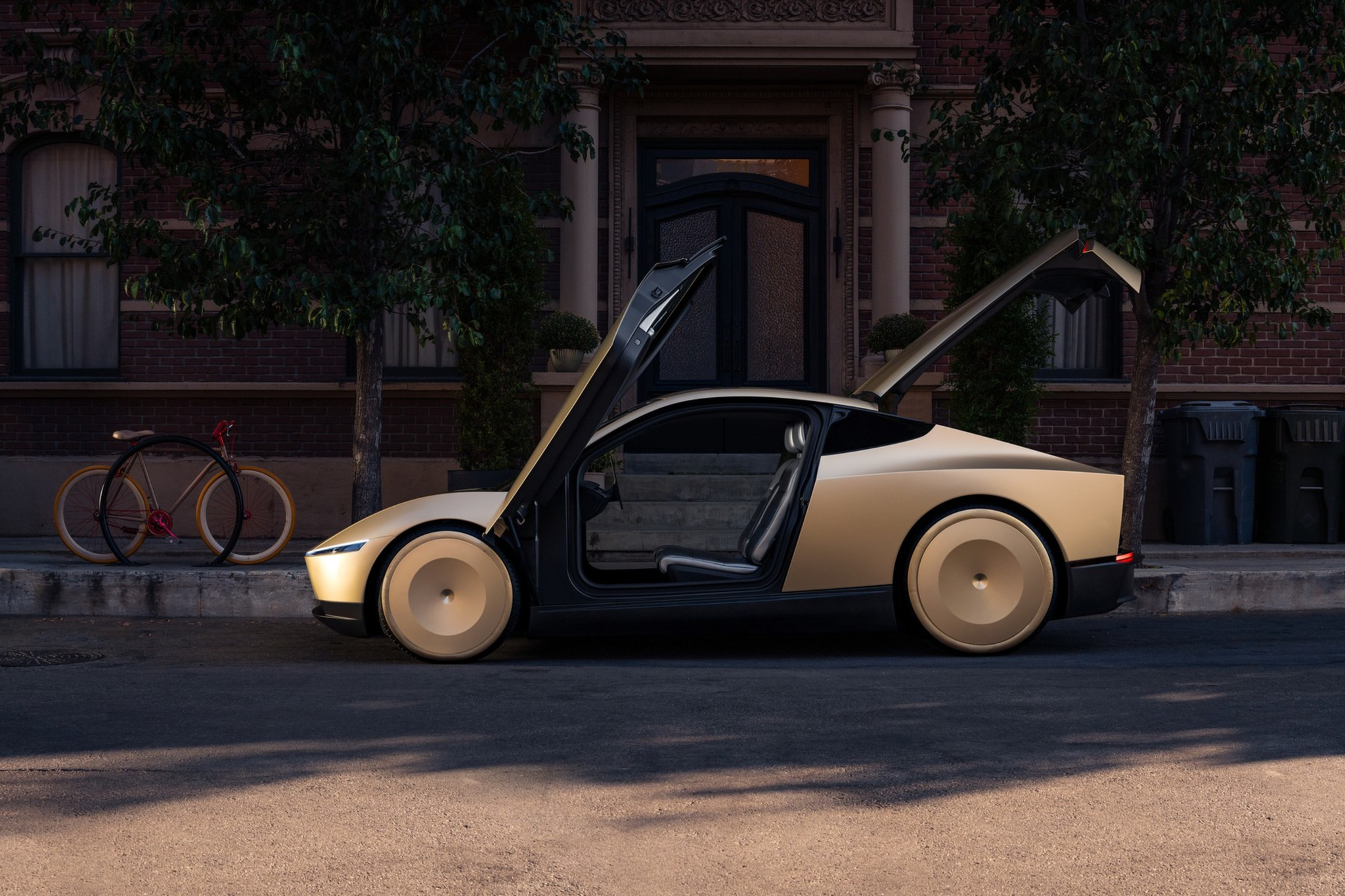 A sleek, beige sports car with both doors and the trunk open is parked on a quiet street in front of a brick building.