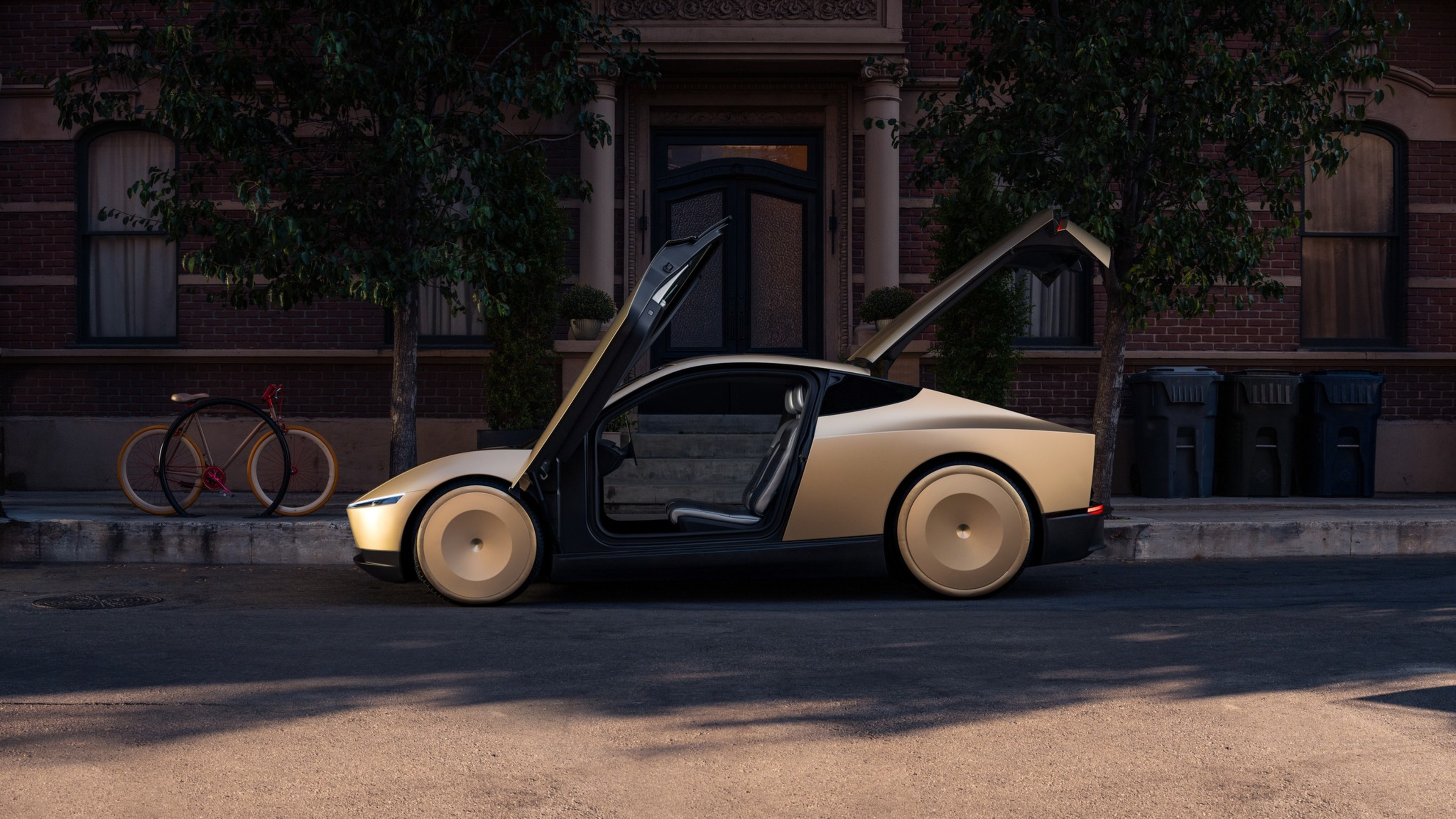 A sleek, beige sports car with both doors and the trunk open is parked on a quiet street in front of a brick building.