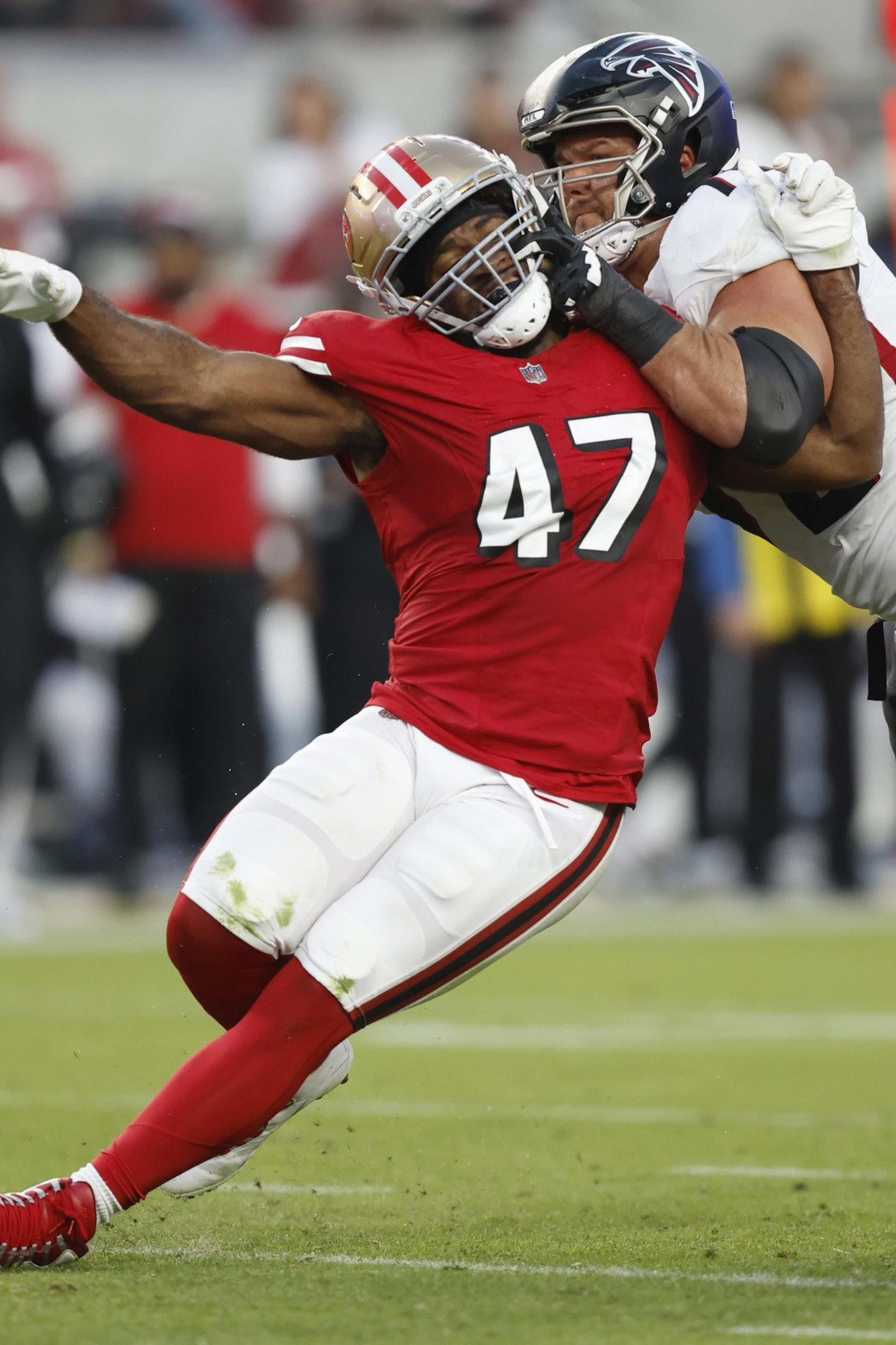 A San Francisco 49ers player wearing number 47 is being blocked by an Atlanta Falcons player while the Falcons quarterback, number 9, prepares to throw the ball.