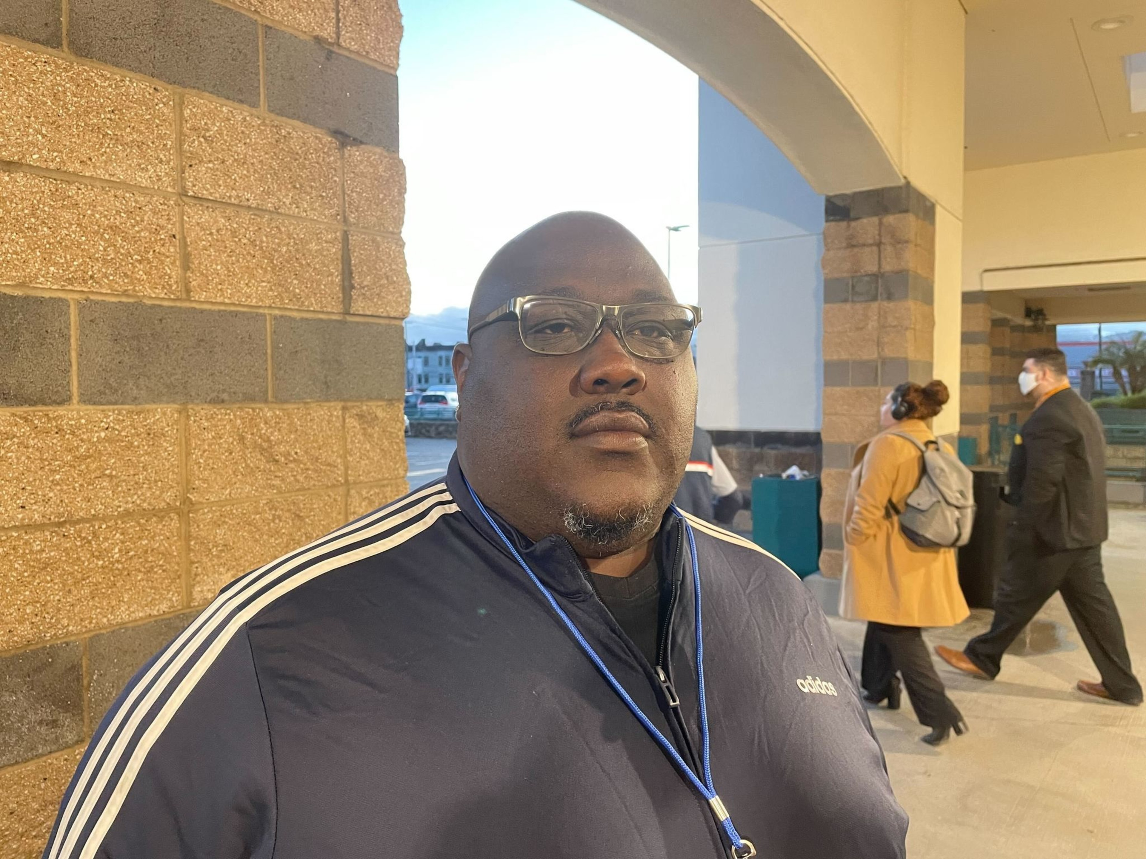 A man stands in front of a grocery store.