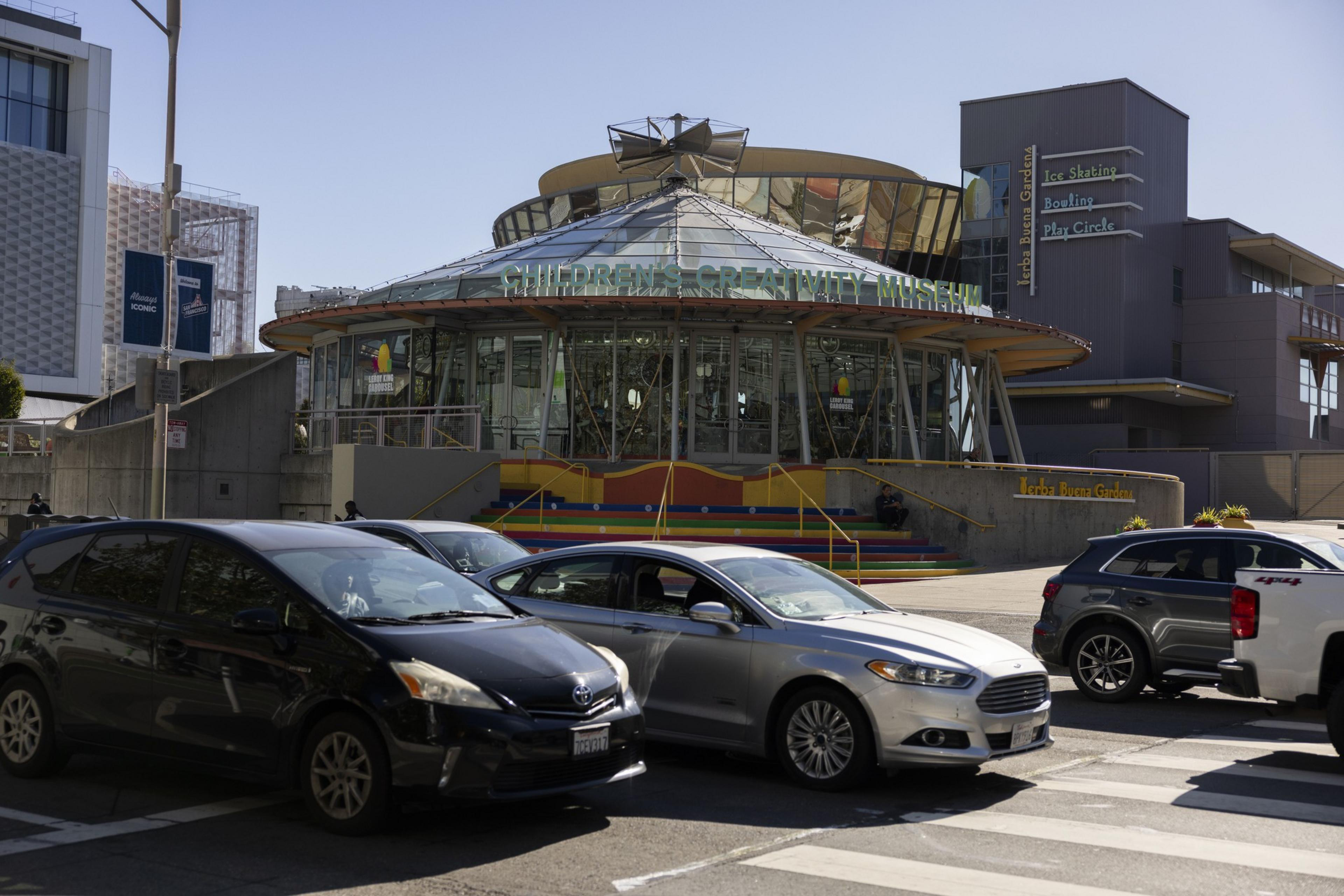 Several cars pass through an intersection on Howard at 4th Street by the Childrenâ€™s Creativity Museum and carousel.