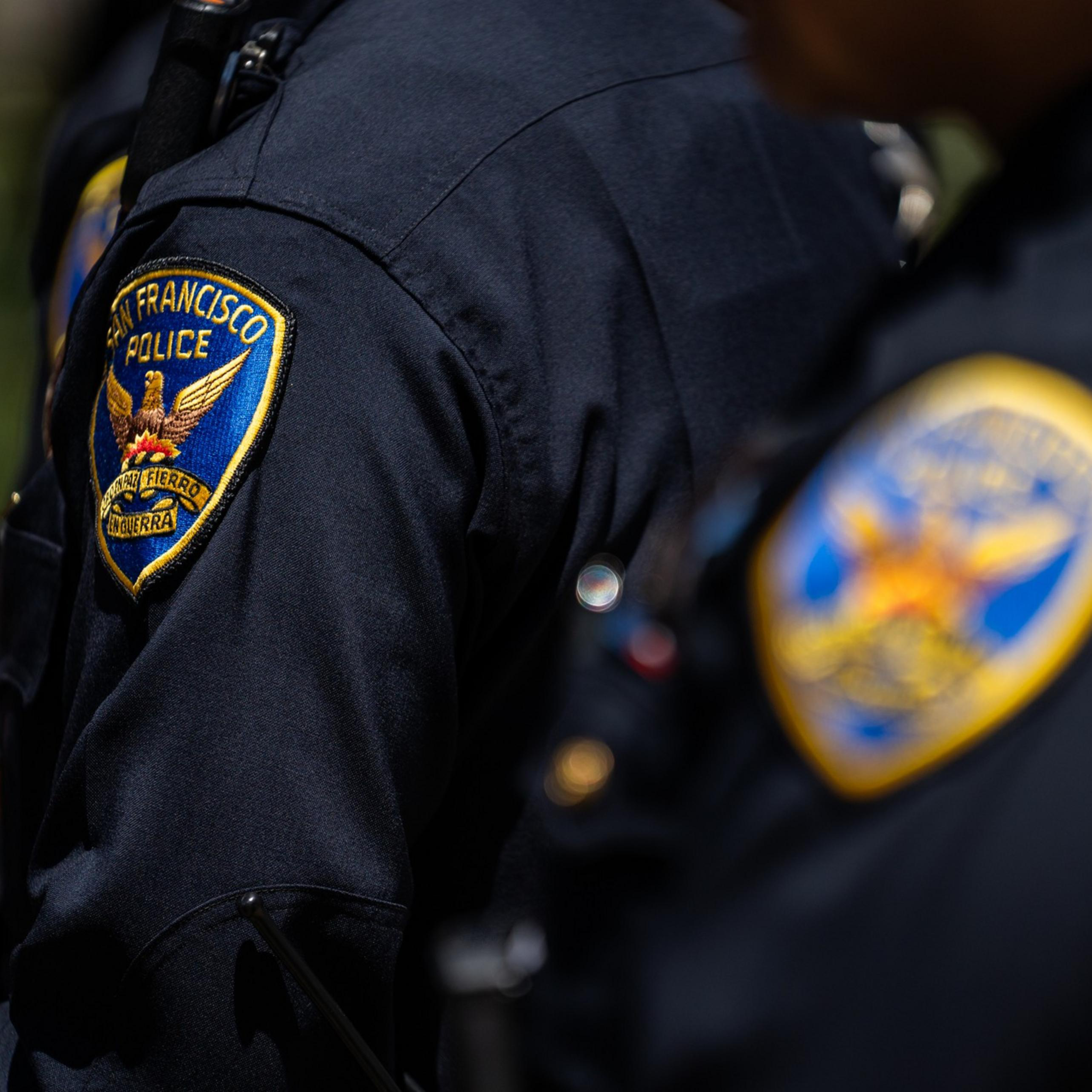 Two San Francisco police officers are shown from the shoulders up wearing dark blue uniforms with visible department patches.