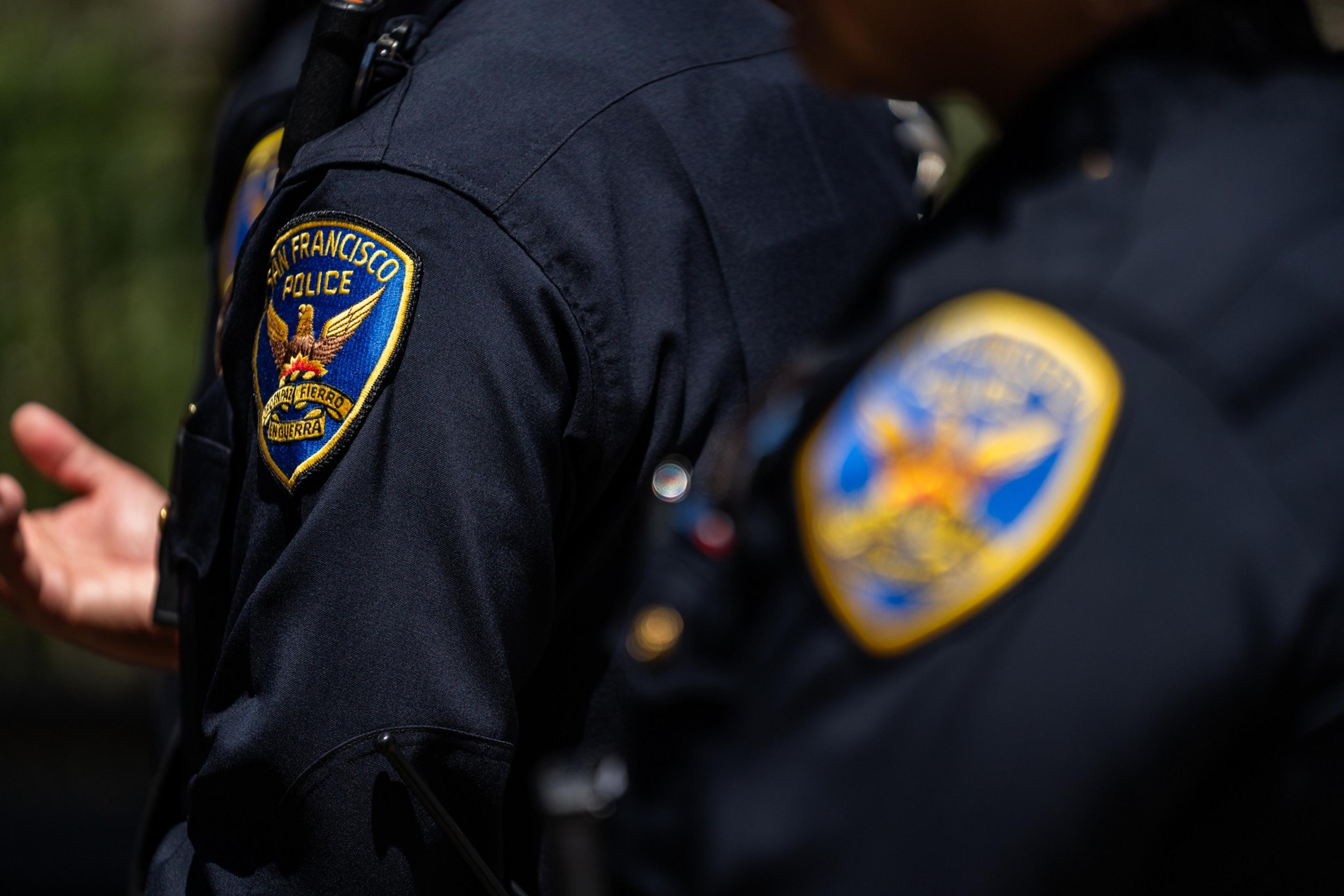 Two San Francisco police officers are shown from the shoulders up wearing dark blue uniforms with visible department patches.