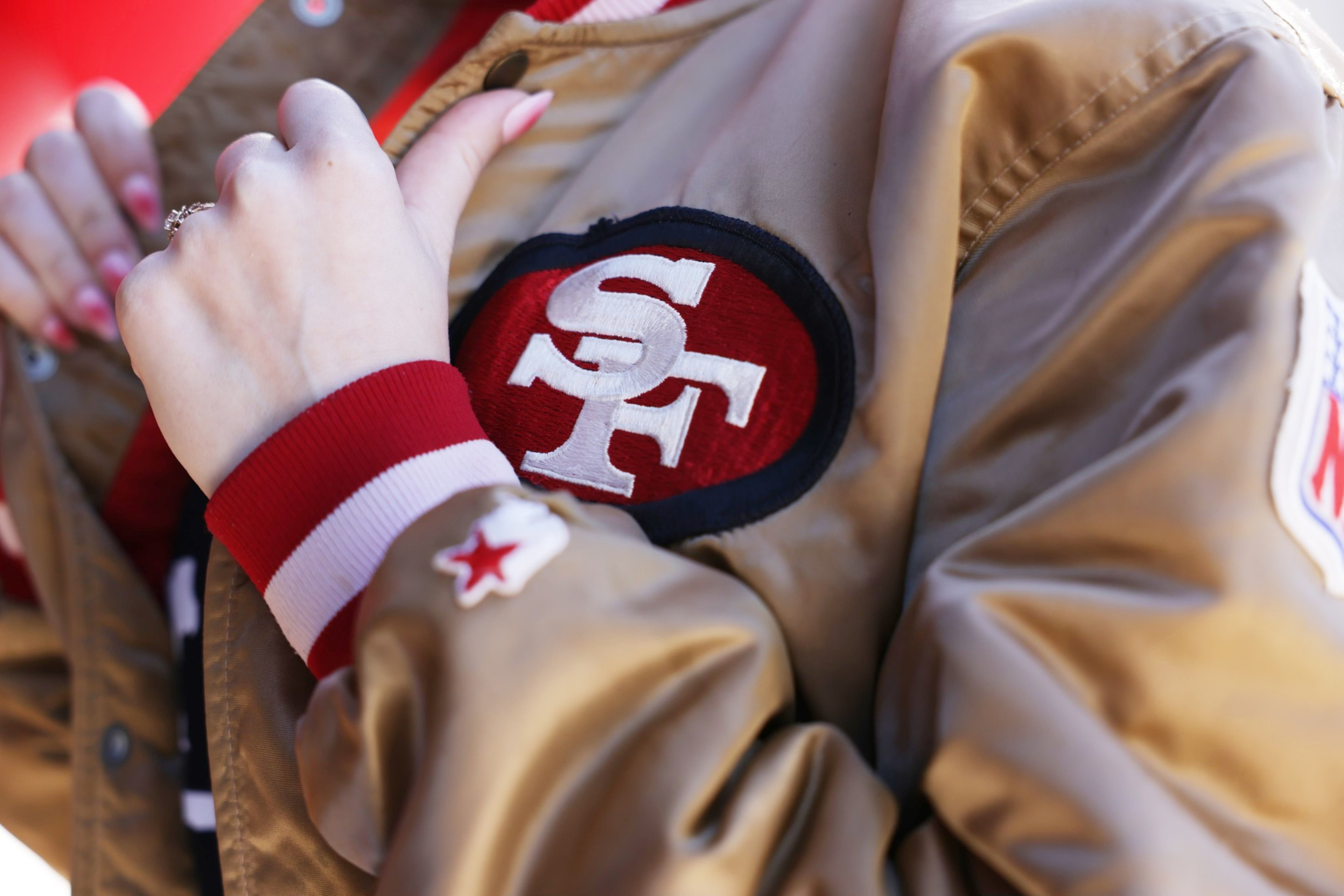 A person adjusts the opening of their gold 49ers starter jacket
