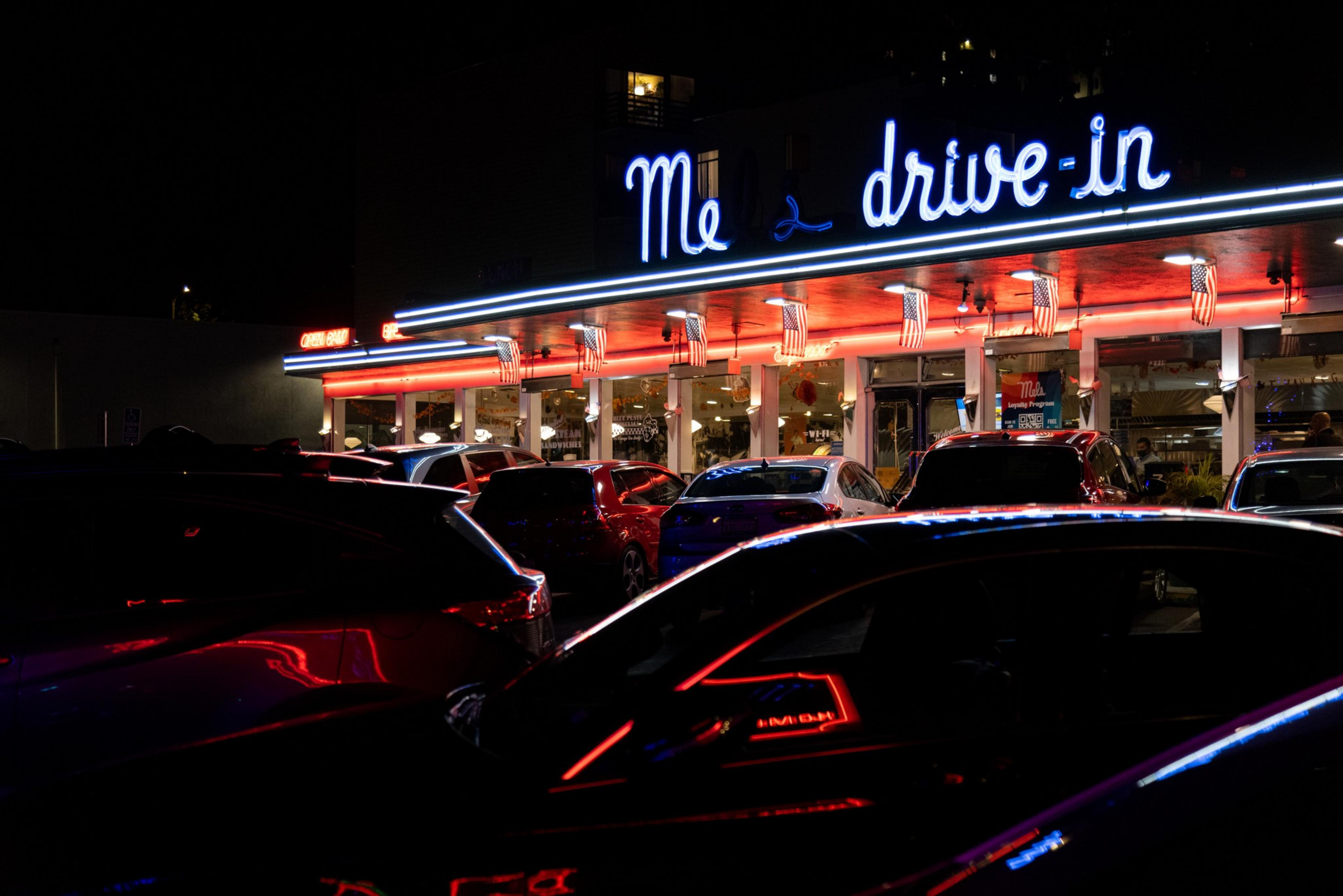A neon sign at night with the words &quot;Mels Drive-in&quot;