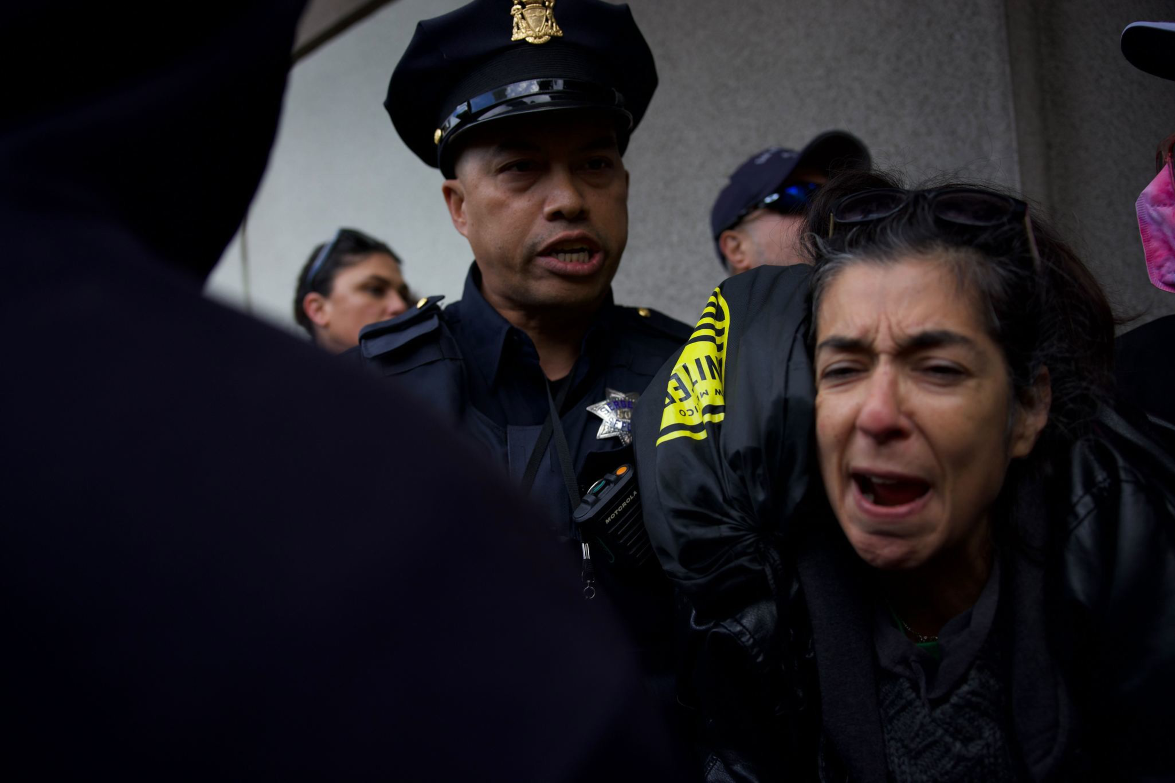 A SFPF officer pushes a person who is grimacing.