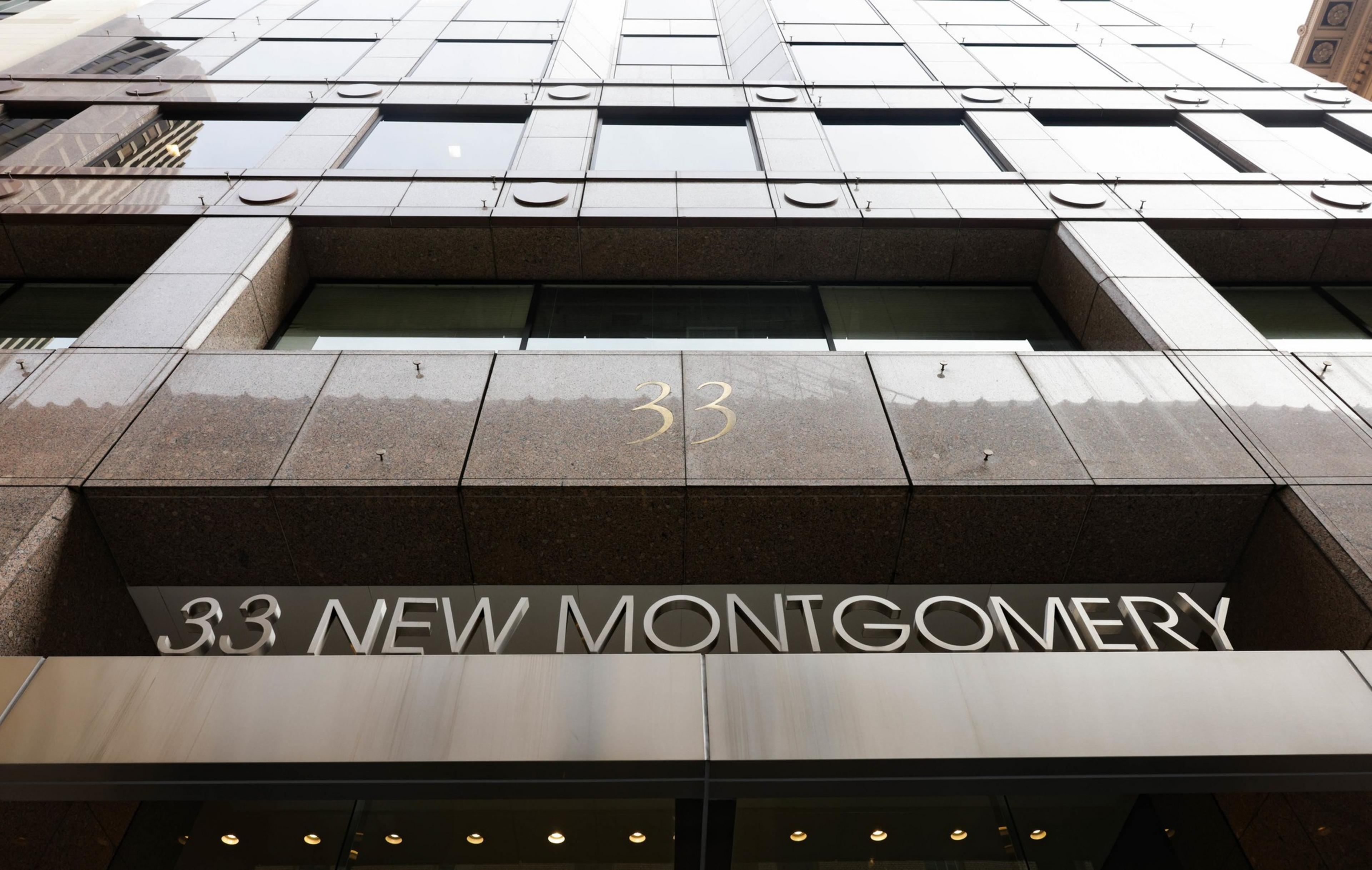 An office building with brown and gray marble with 33 New Montgomery in letters.