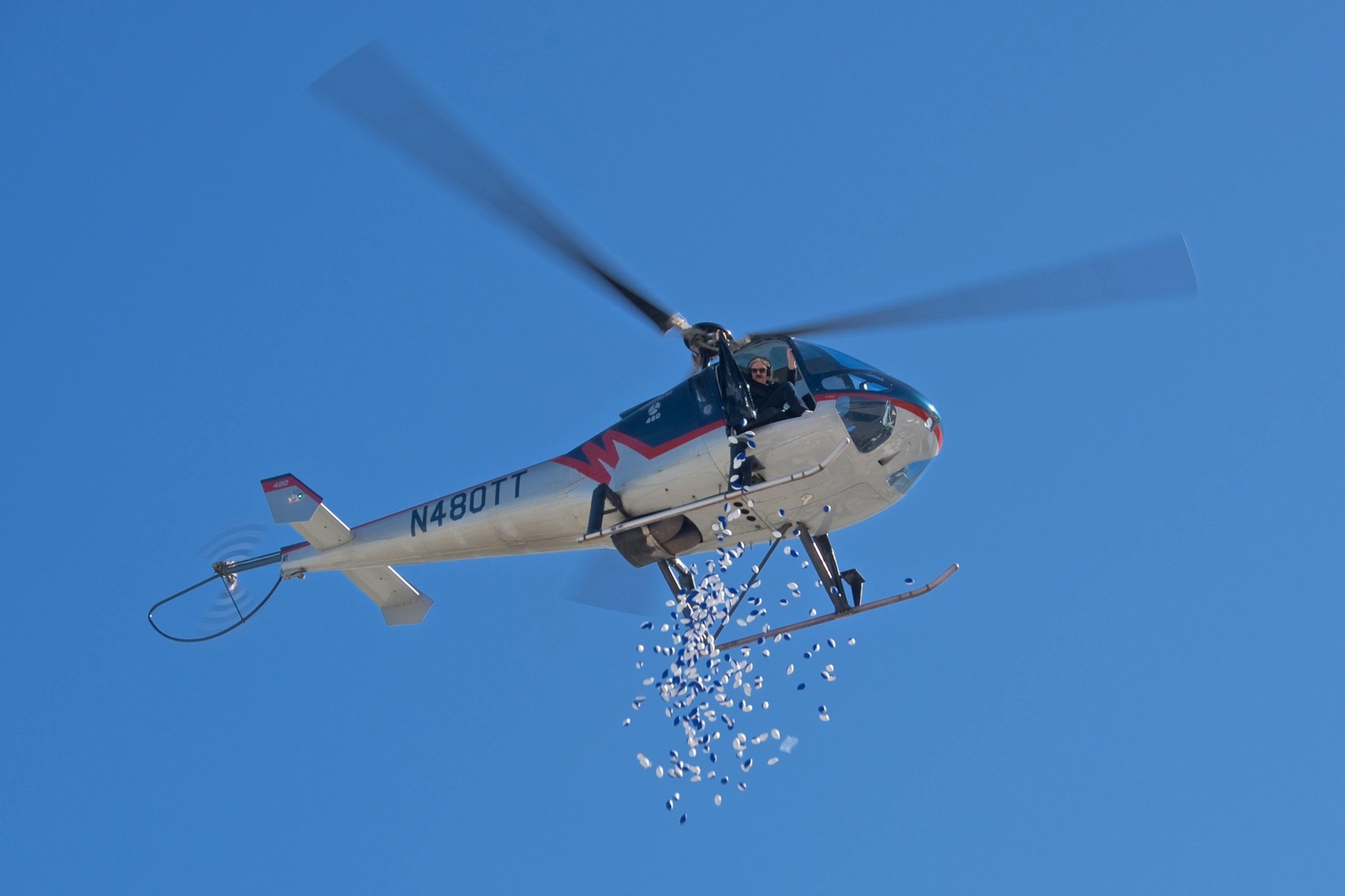 A flying helicopter  drops foam blue mini footballs from the sky. 