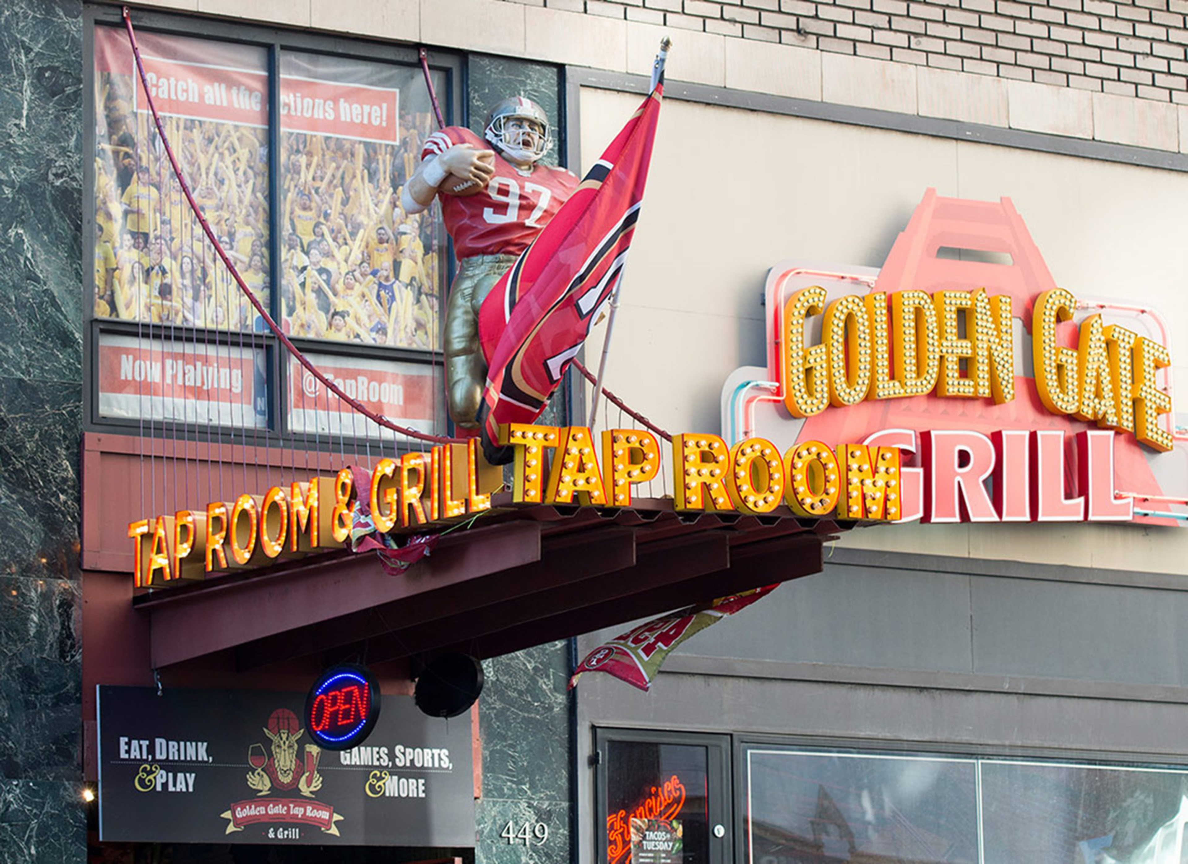 A restaurant sign reads "Golden Gate Tap Room & Grill" with a football player statue holding a ball and flag above it.