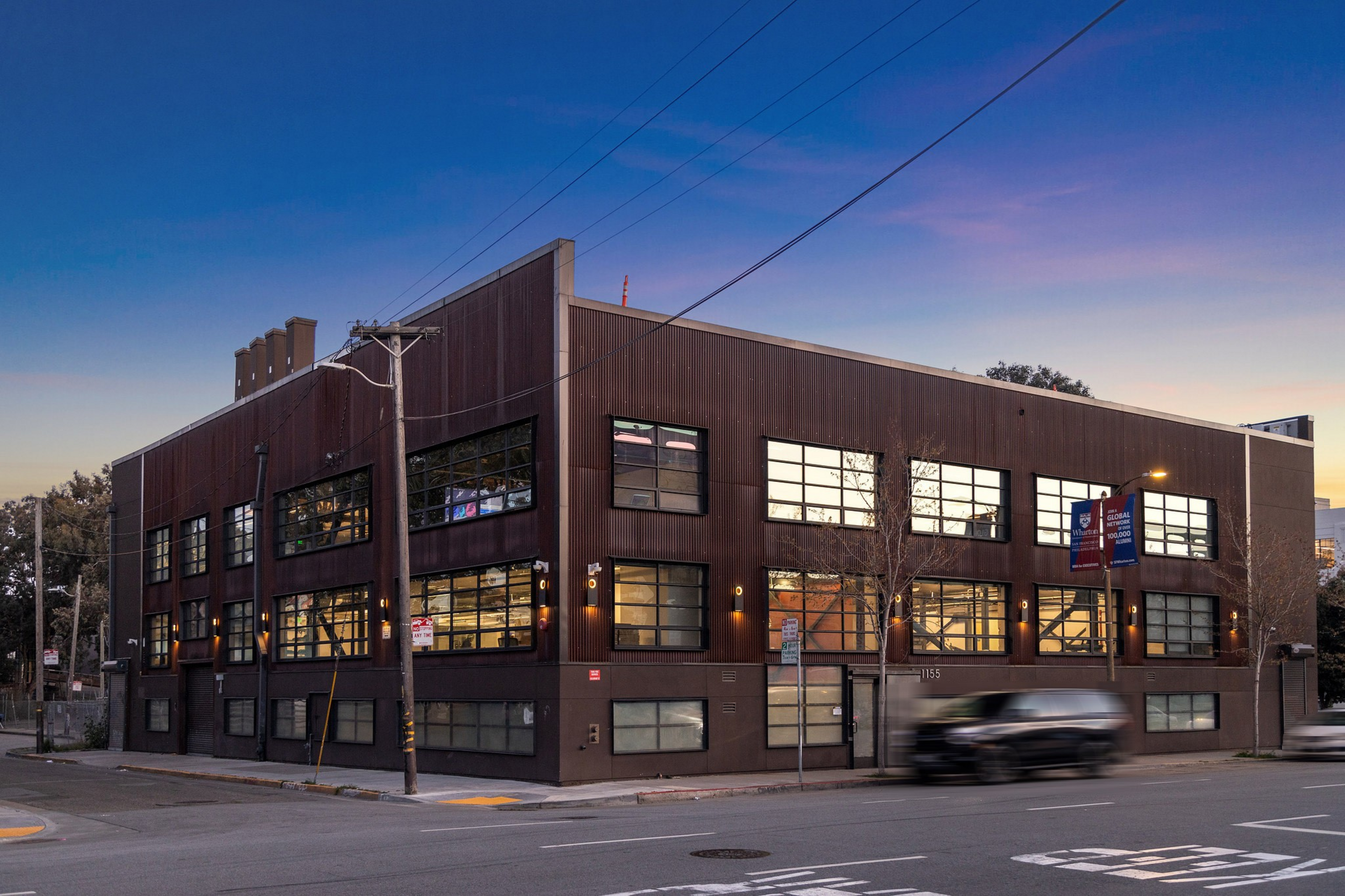 A two-story brown industrial-style building sits on a street corner at ...