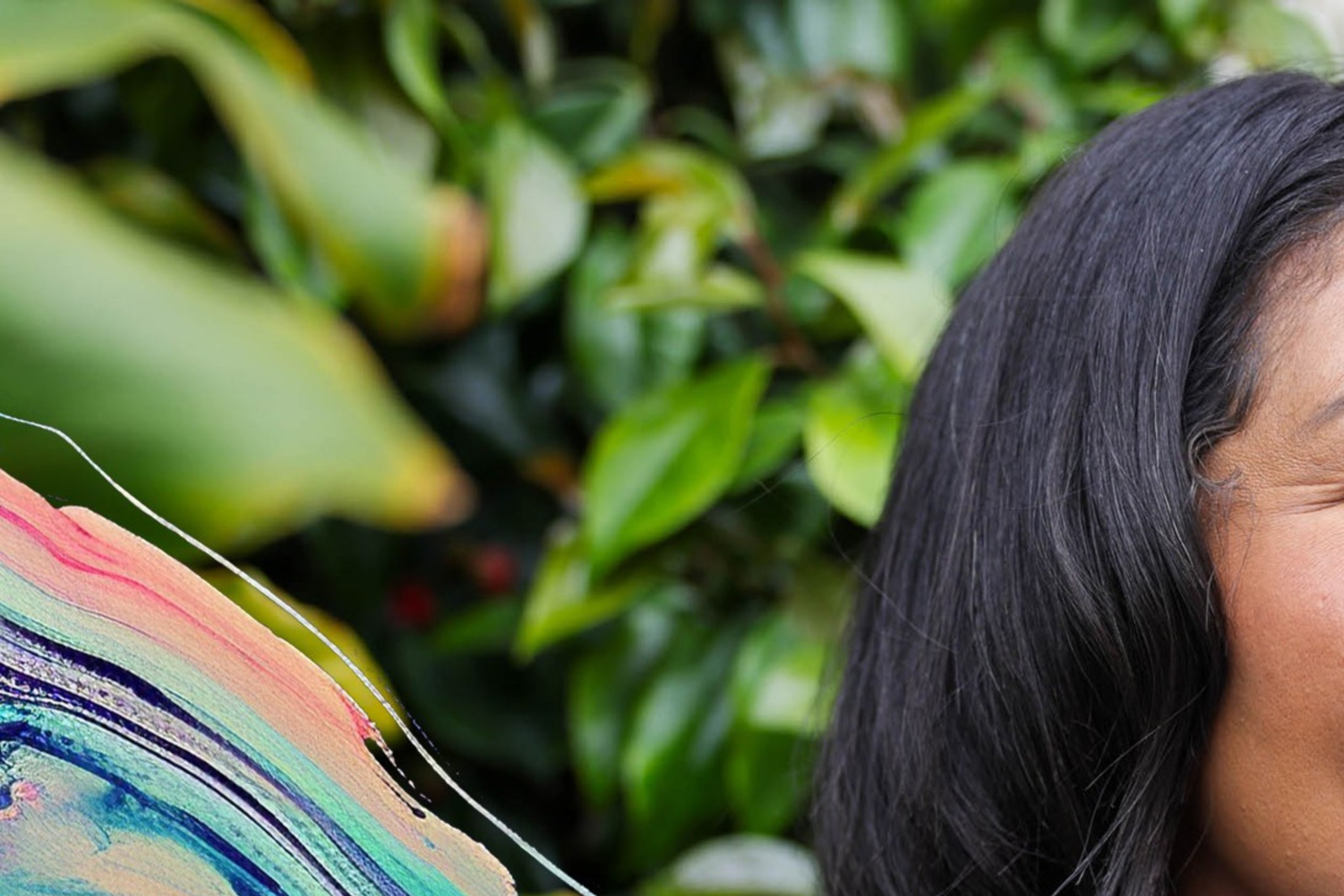 London Breed, the mayor of San Francisco, wears a purple dress in front of green foliage.