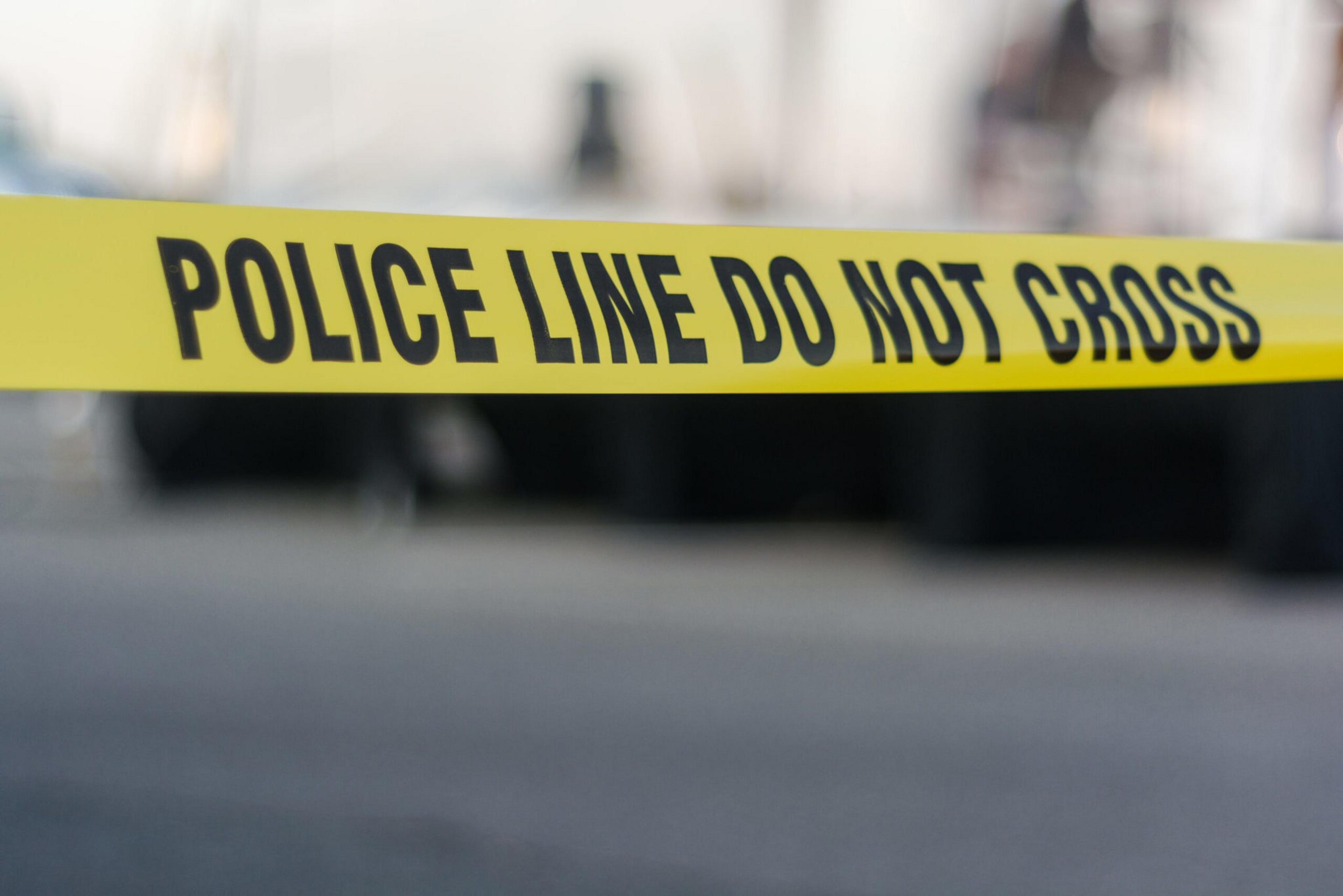 Yellow police tape stretches across a distant scene and warns viewers not to cross its path