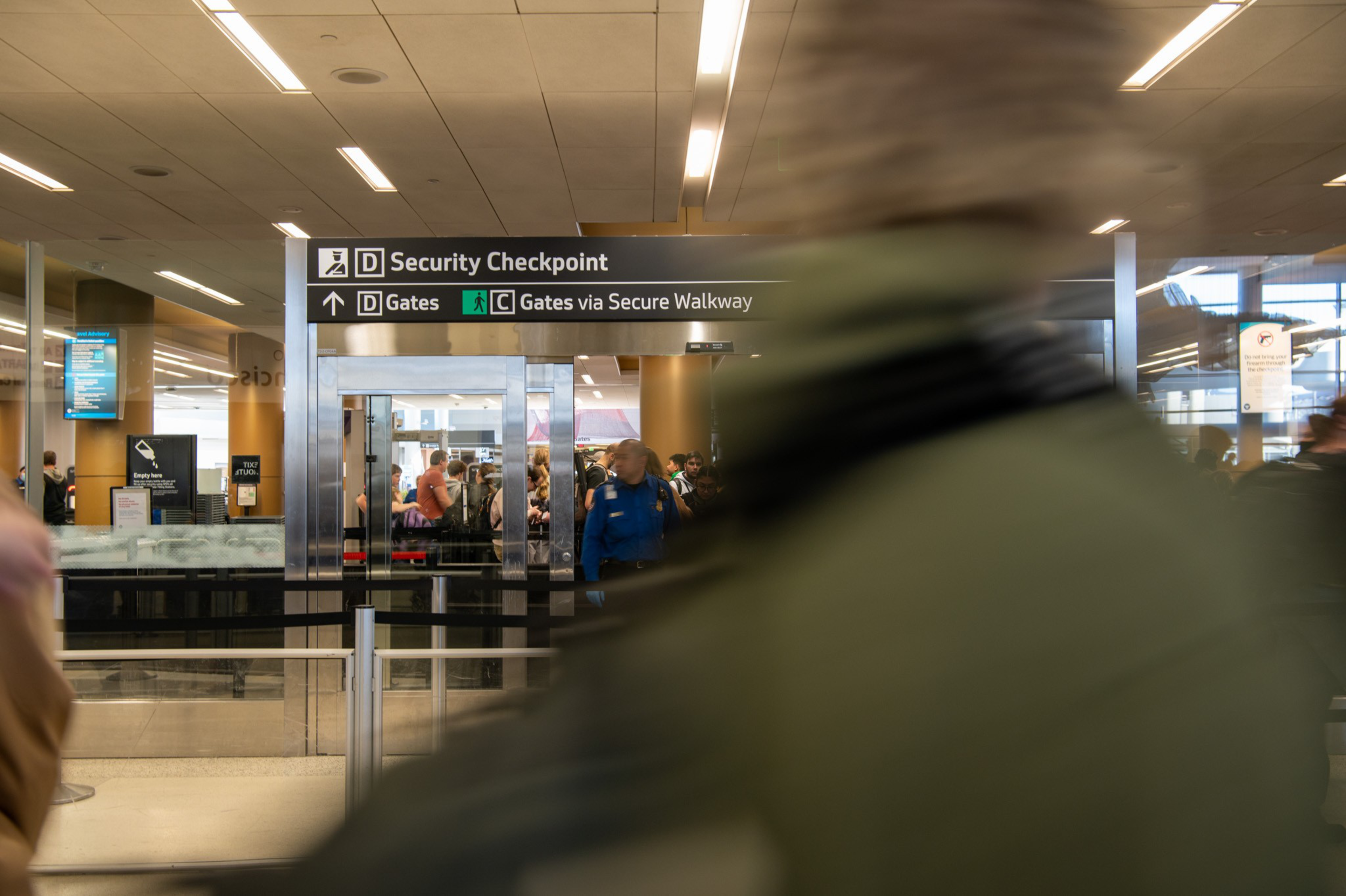 A security checkpoint as people wait in line and TSA agents checking boarding passes and id's.