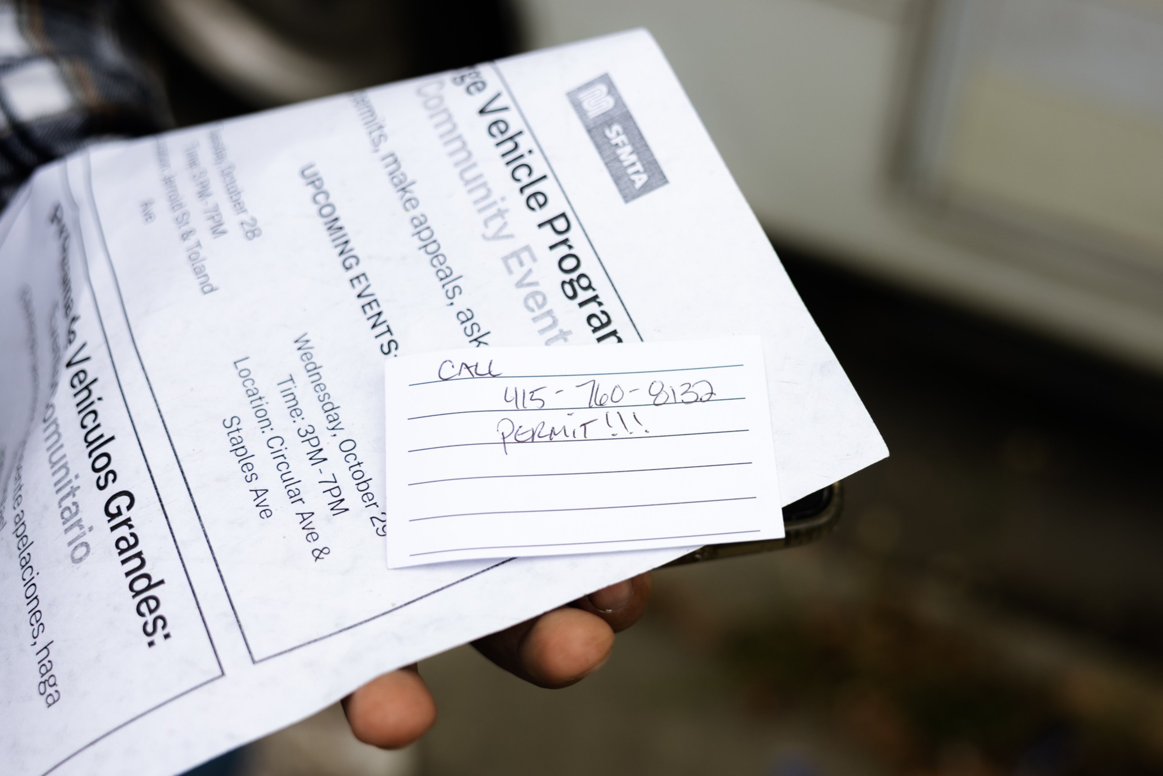 A hand holds papers including a flyer about a vehicle program and a handwritten note reading “CALL 415-760-9137 PERMIT!!!”.