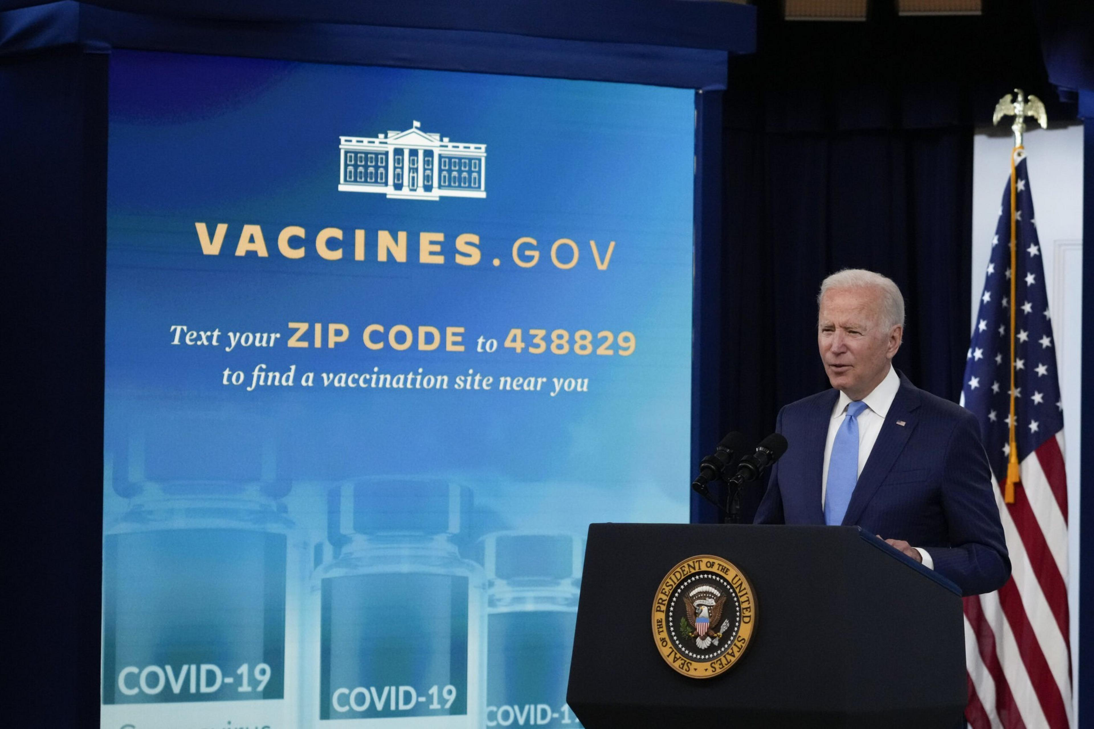 President Joe Biden stands at a podium with the presidential seal next to a screen promoting vaccines.gov and a text service for finding COVID-19 vaccination sites.