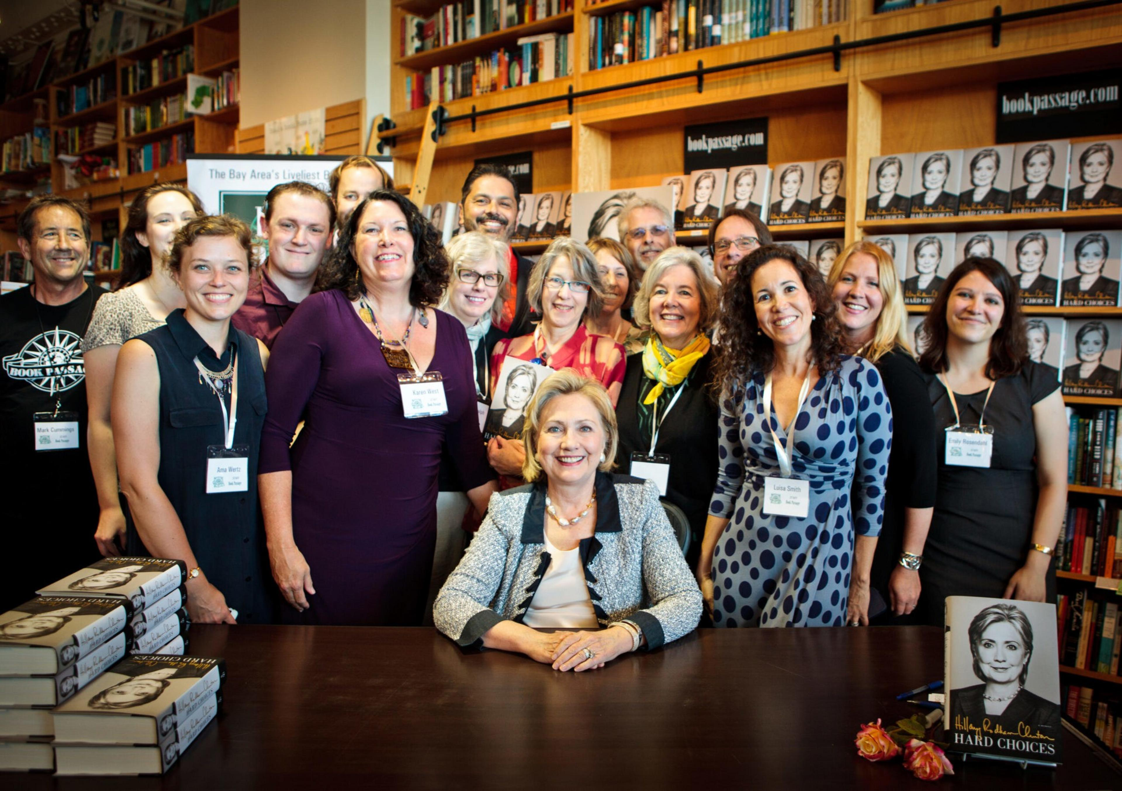 A crowd of people smiling in front of book shelves. 